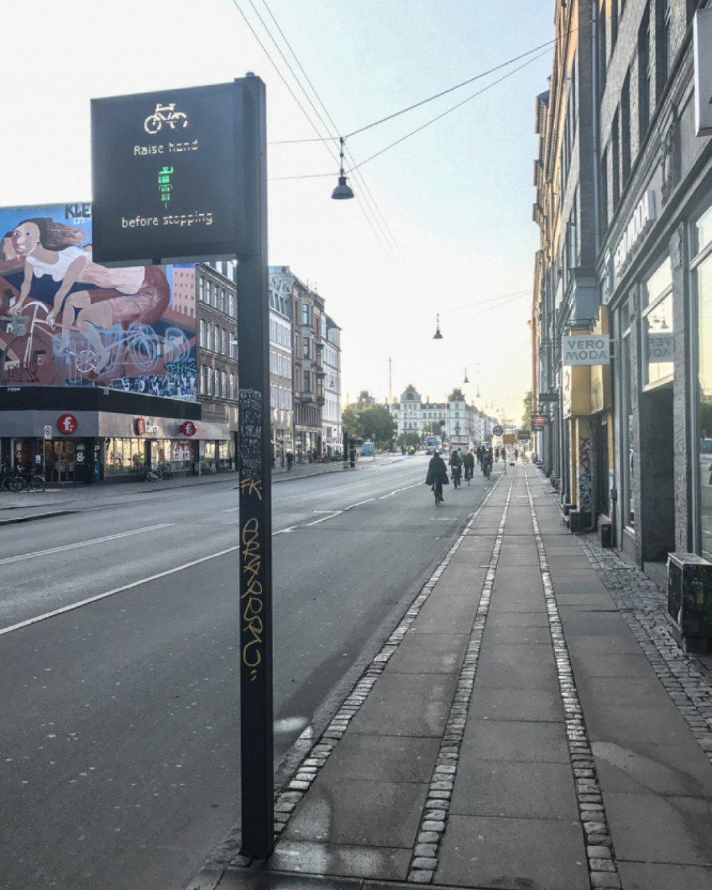 Billboard advertisement featuring cycling imagery on Copenhagen street with historic buildings and cobblestones