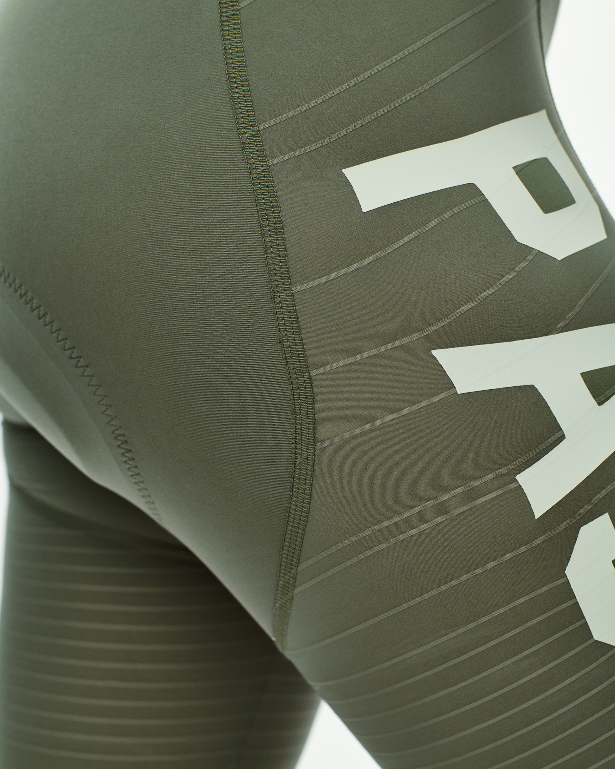 Green PAS Mechanism Pro bibs, detail view with white side logo and flatlock seams