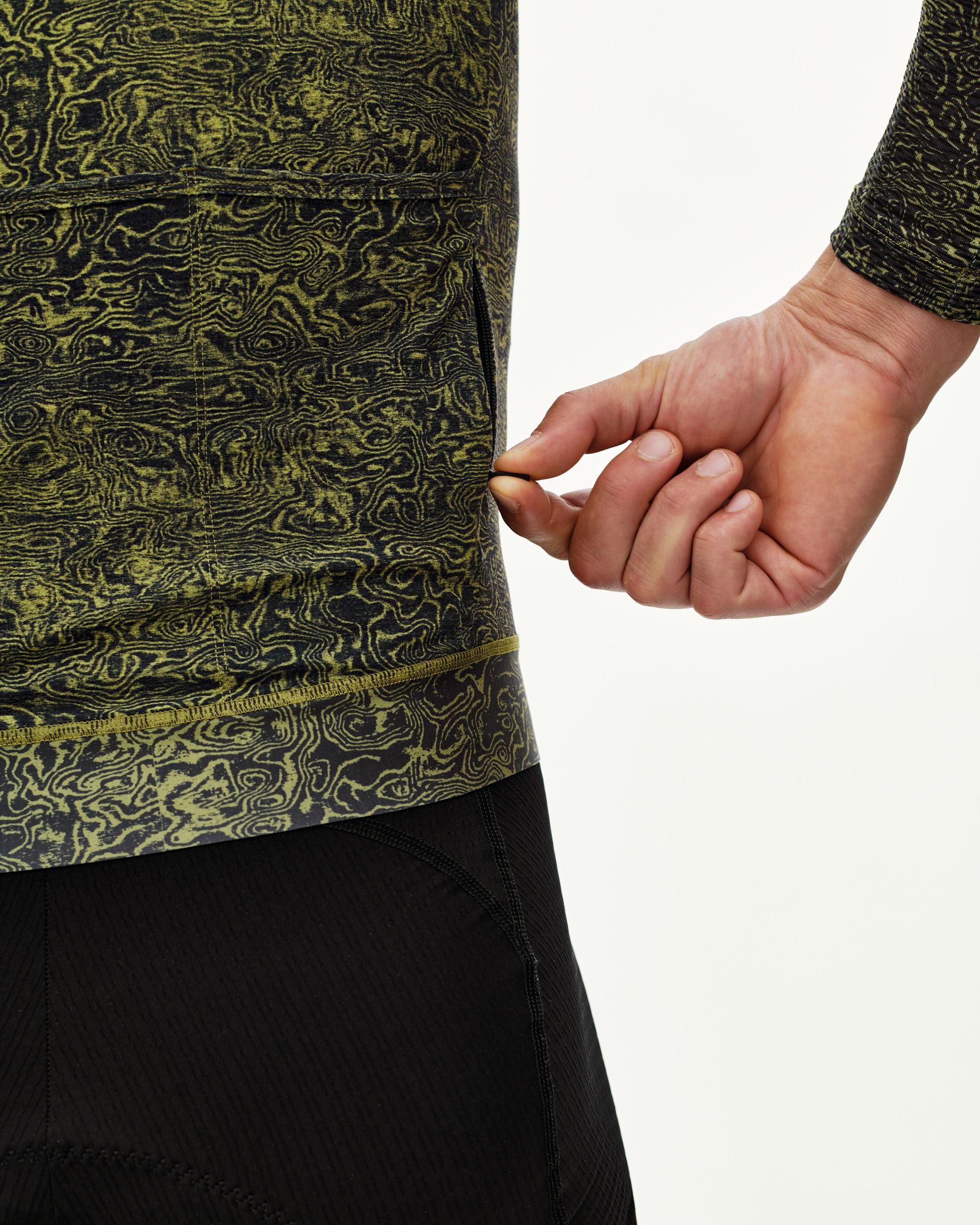 Dark Lime Essential long sleeve cycling jersey, side detail on model with allover topographic print and hem zip pocket