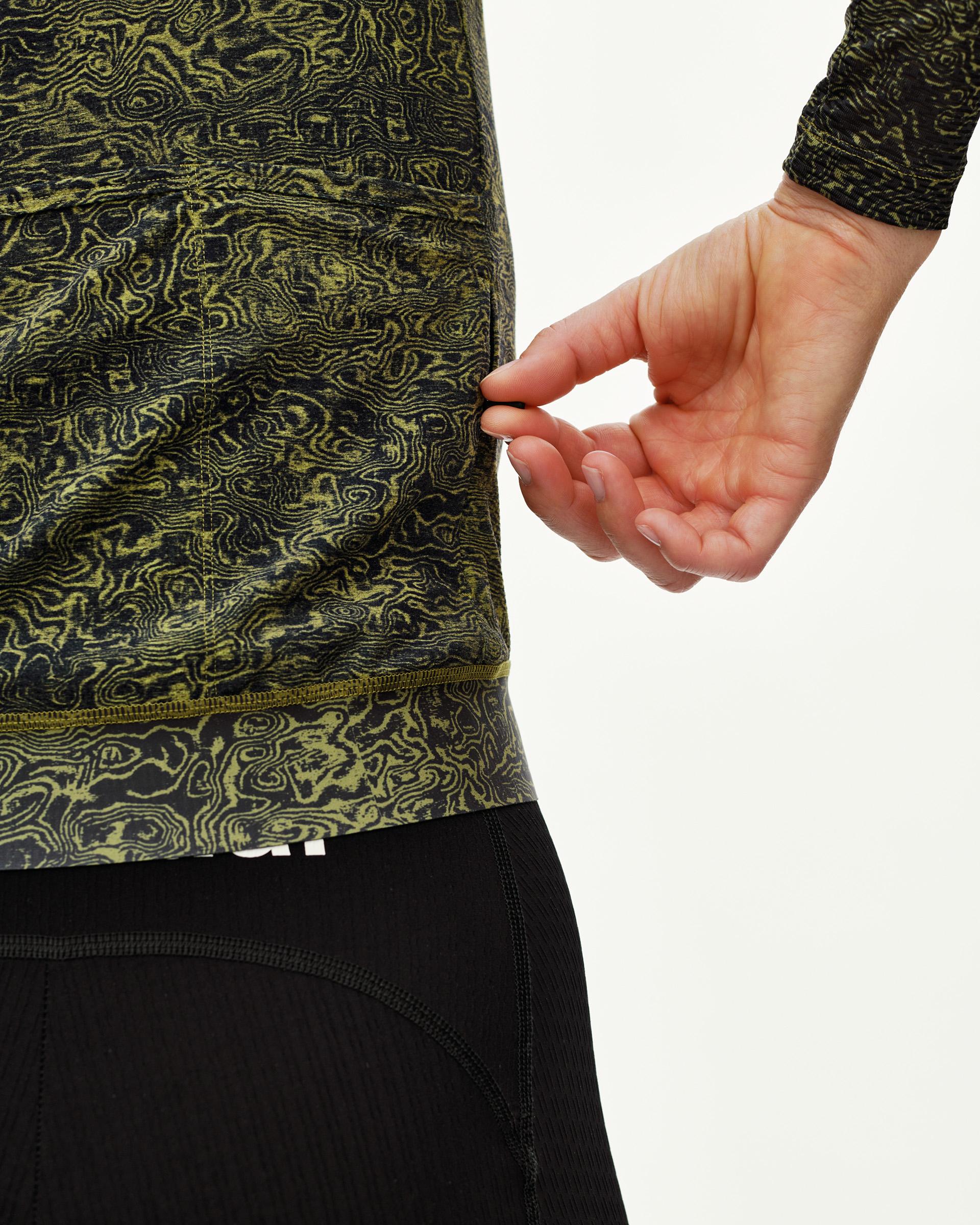 Dark Lime Essential long sleeve cycling jersey, side detail on model with swirl all-over print hem