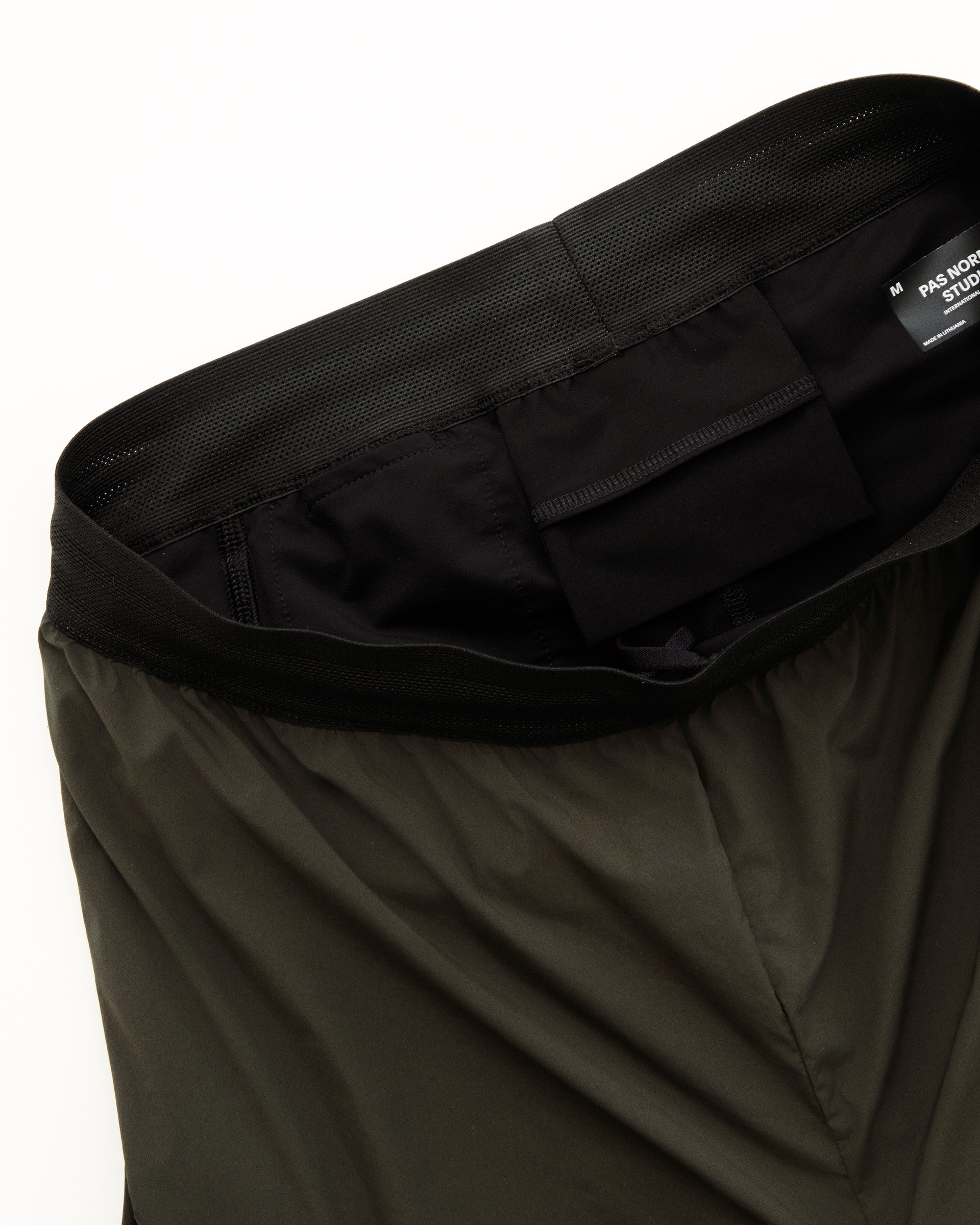 Interior waistband with zippered pocket and elastic loops for secure storage of essentials during cycling