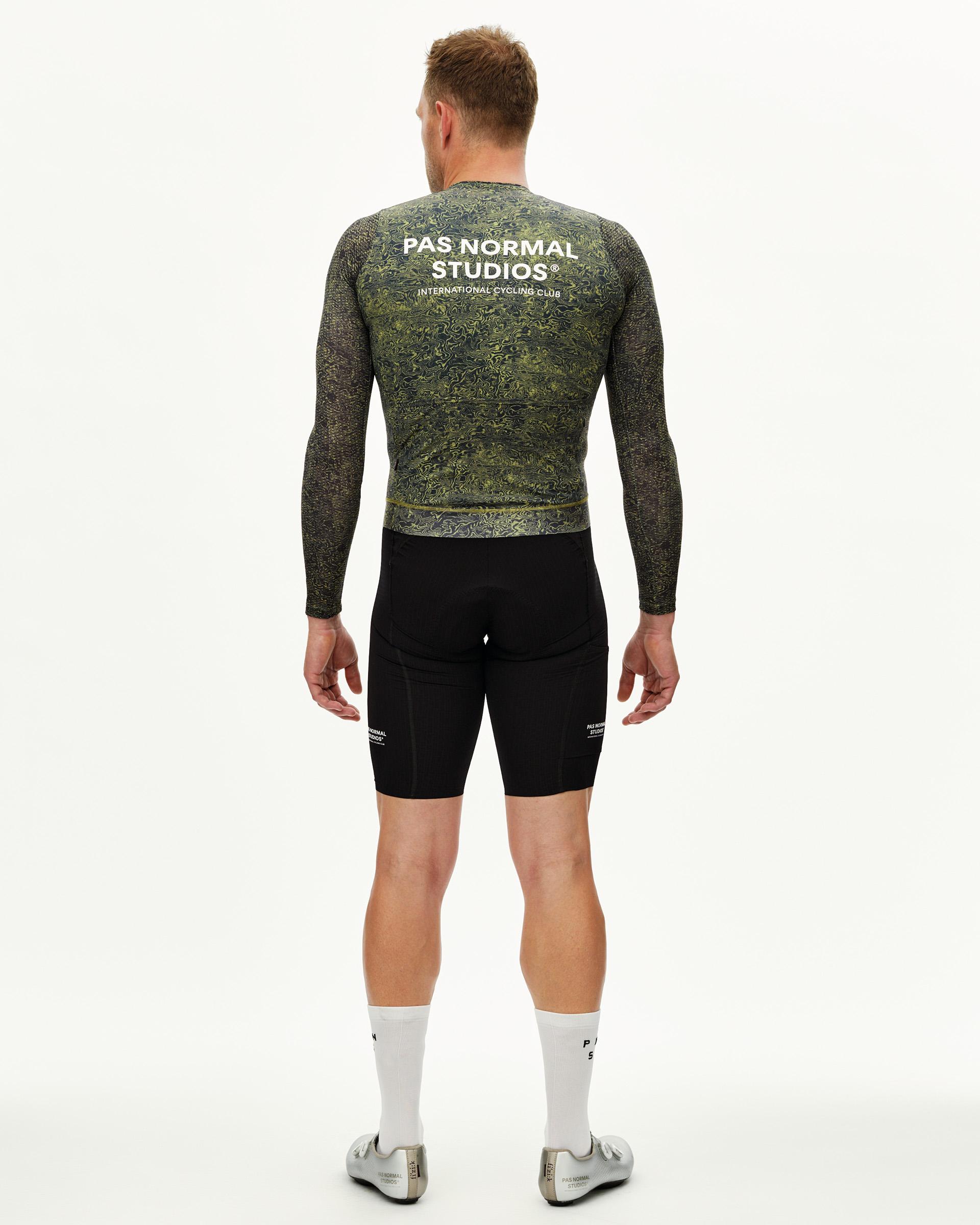 Dark Lime Essential long sleeve cycling jersey on model, rear view with swirling AOP print and white back logo
