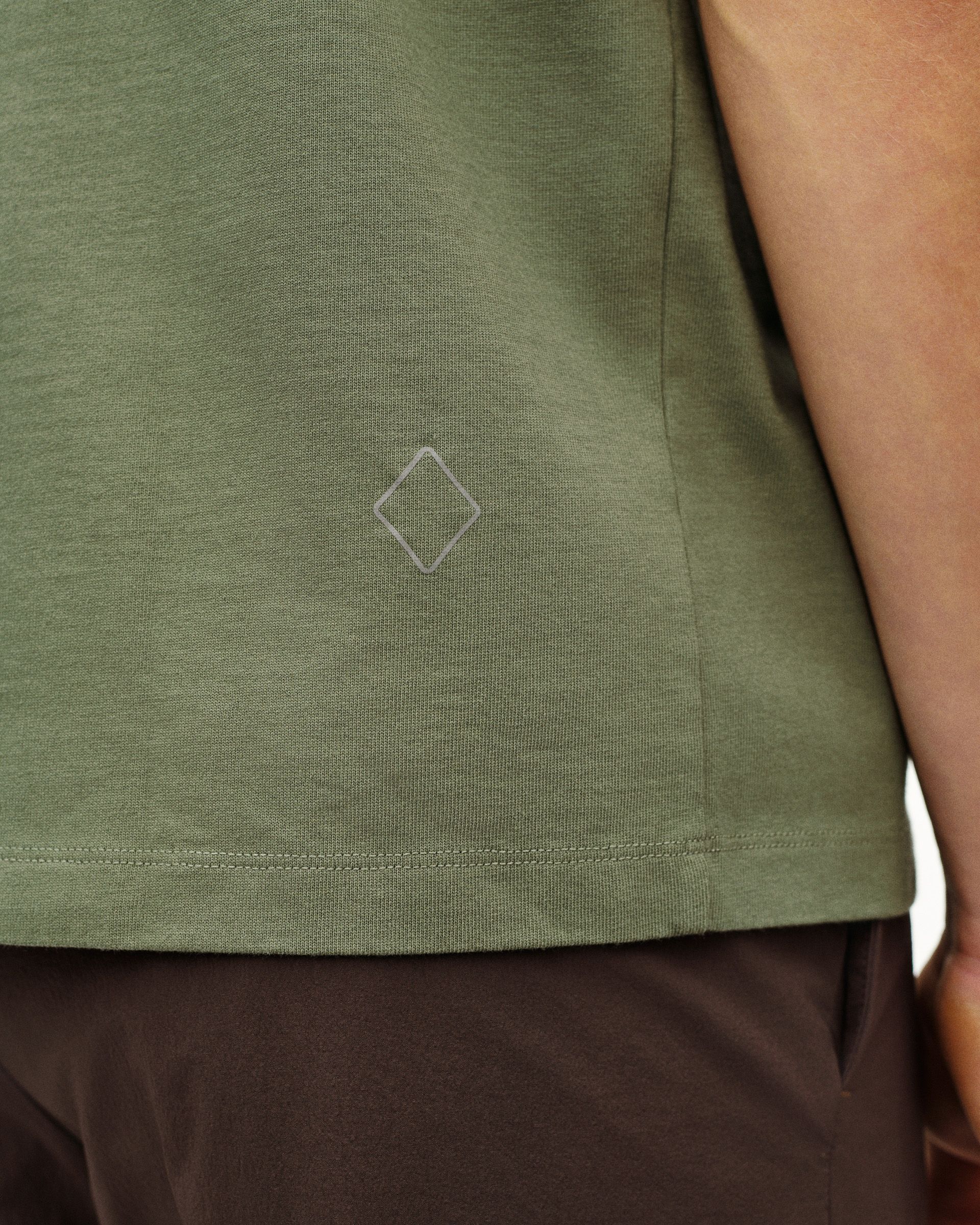 Green Off-Race t-shirt detail view showing diamond logo print on hem