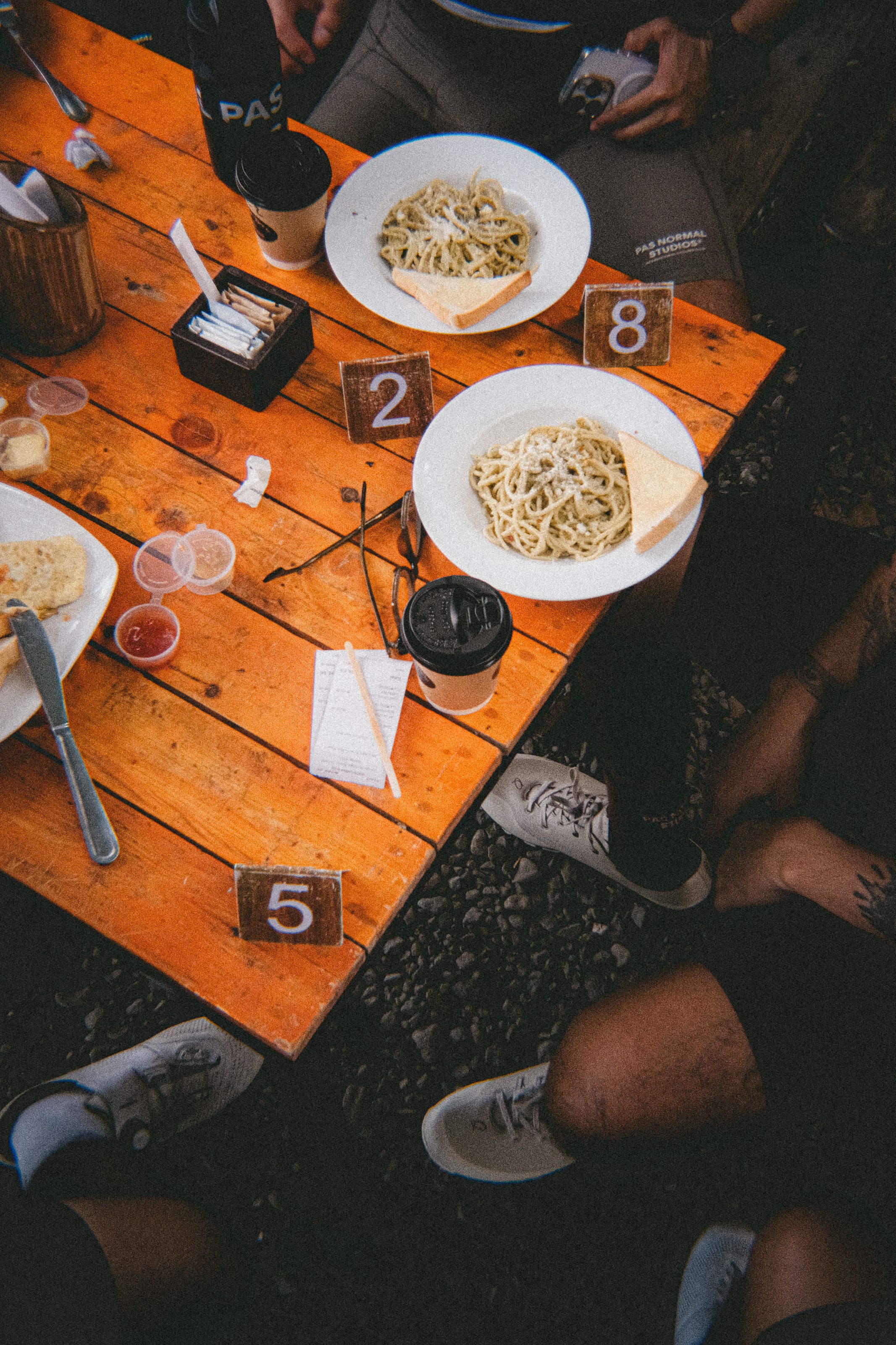 Cyclists refueling with pasta at wooden table during cycling event