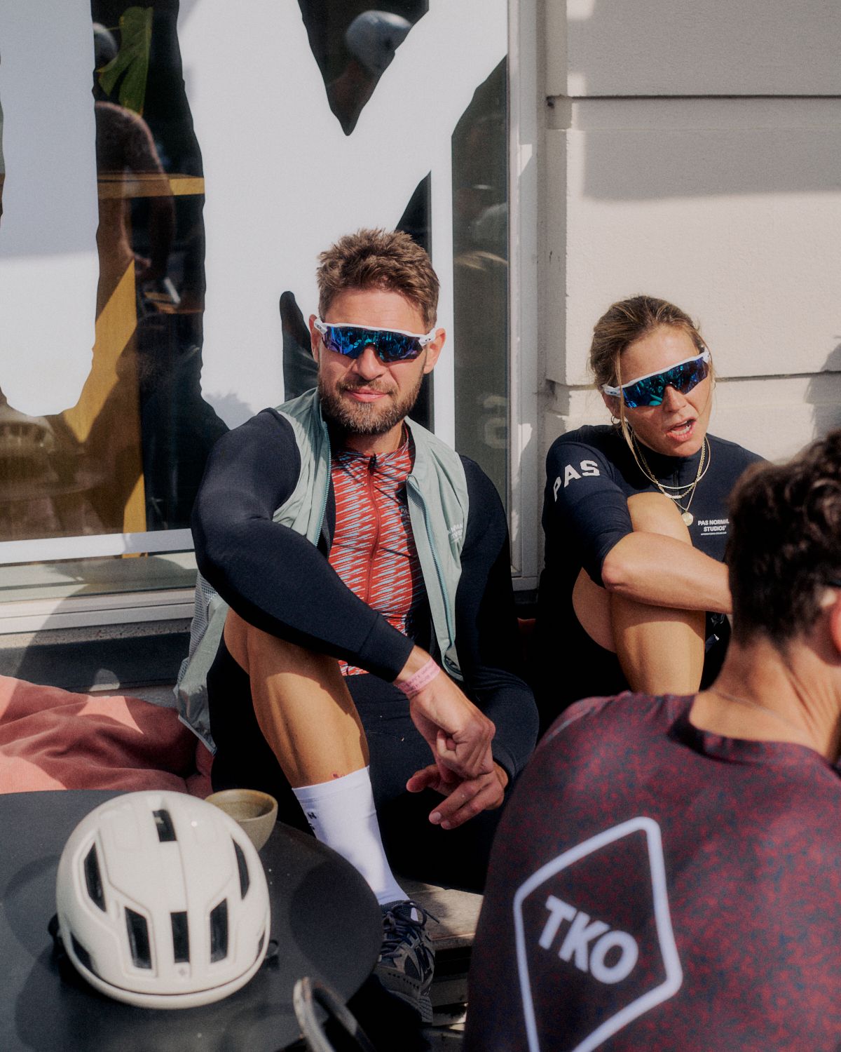 Models wearing PAS collection cycling apparel relaxing after ride with helmets and sunglasses