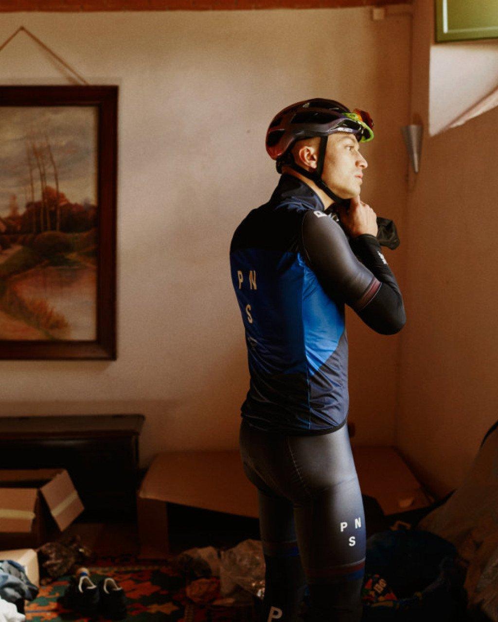 Model wearing Men's PAS Collection blue and black cycling jersey with matching bib shorts indoors