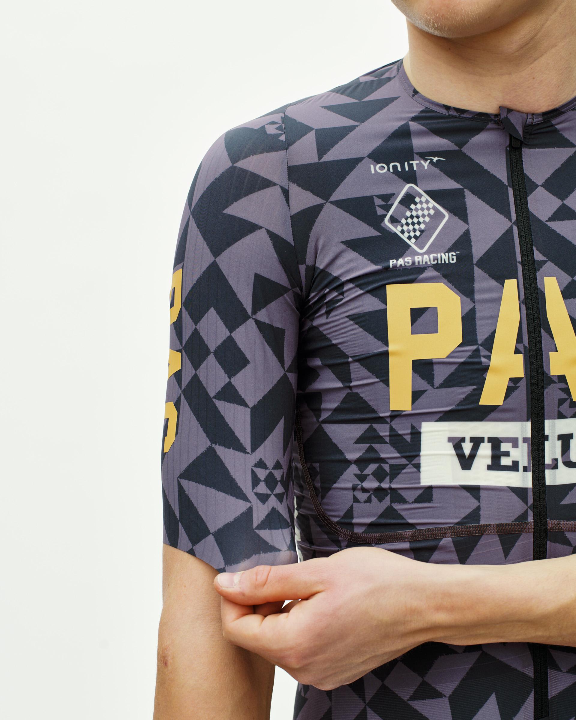 Origami Grey PAS Mechanism Pro cycling jersey on model, front detail with geometric print and gold lettering