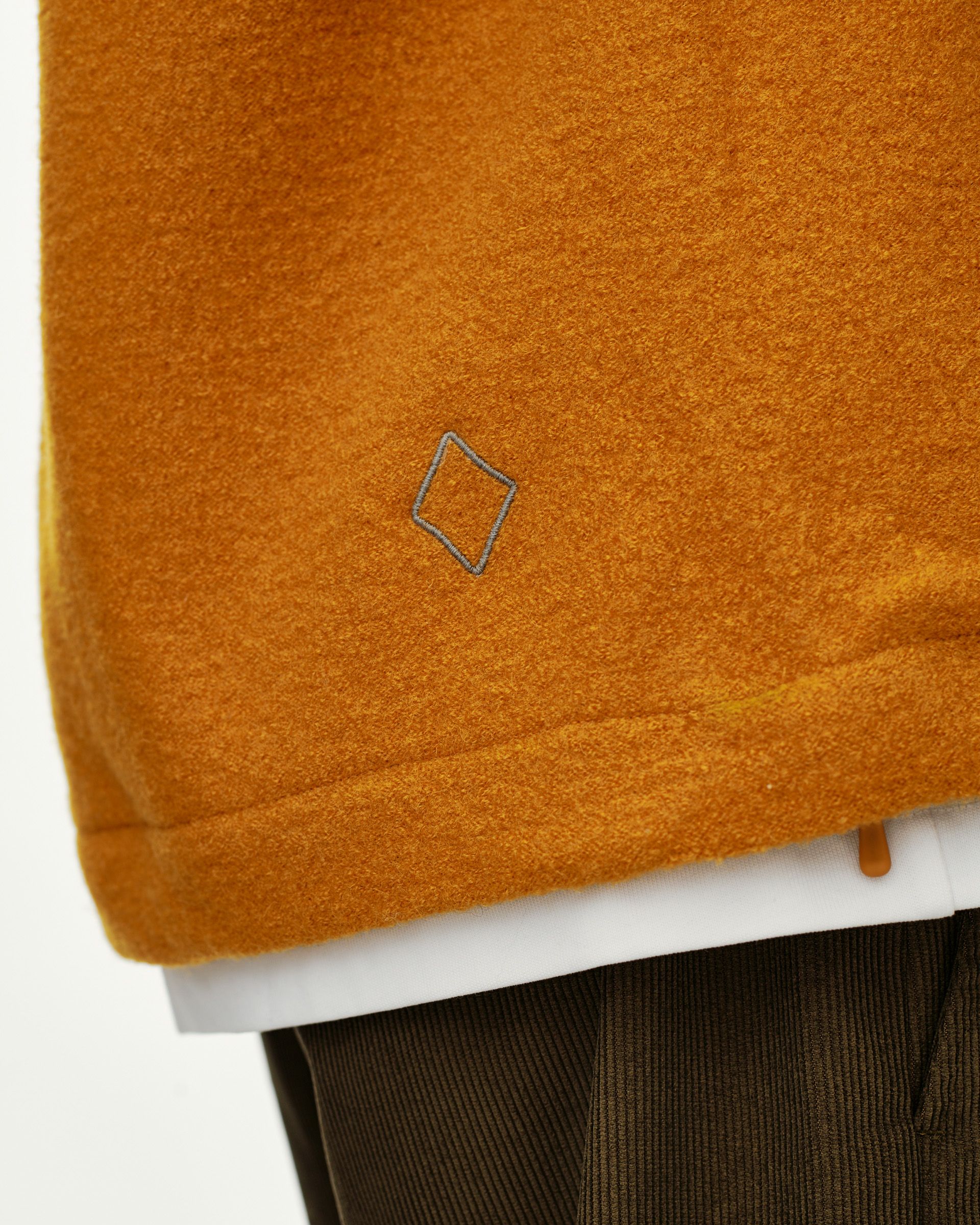 Ochre Off-Race Boiled Wool Half-Zip outerwear, hem detail on model with embroidered diamond logo