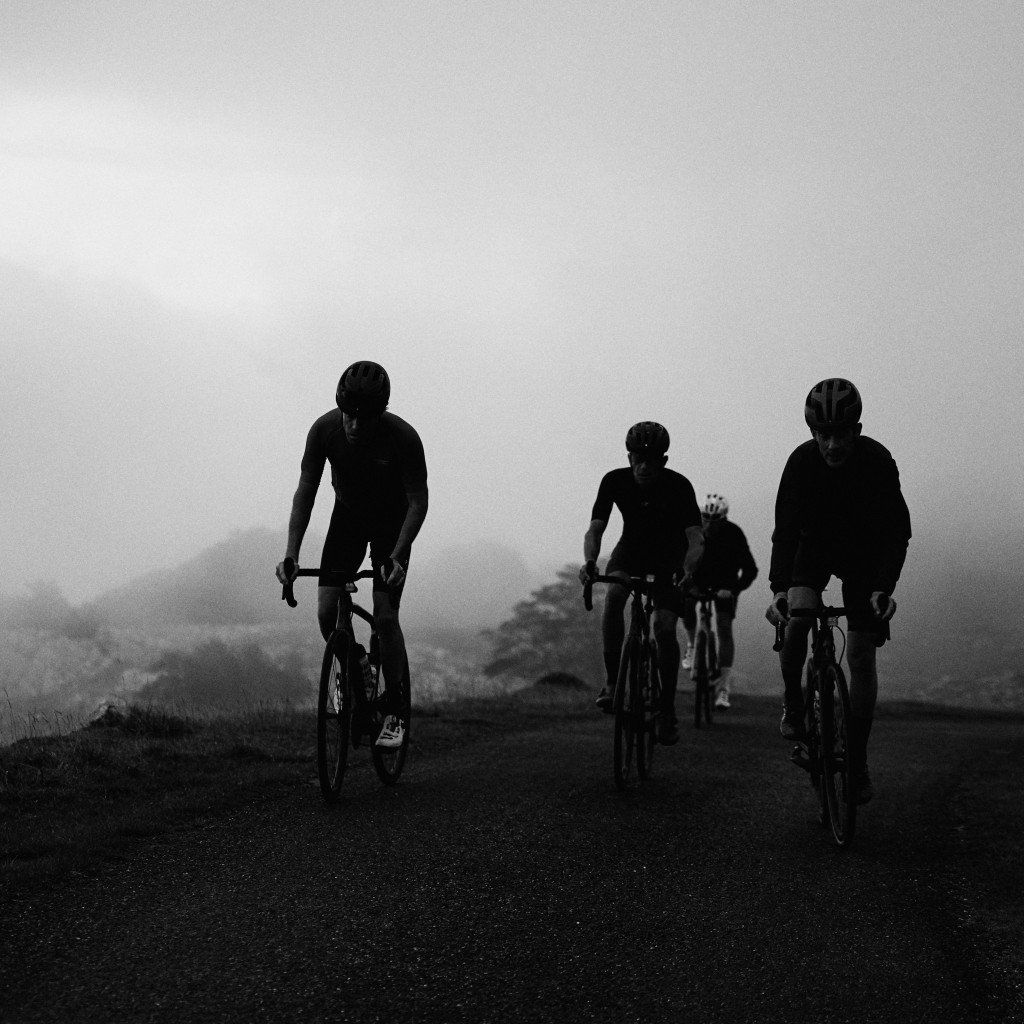 Cyclists silhouetted against misty landscape on rural road