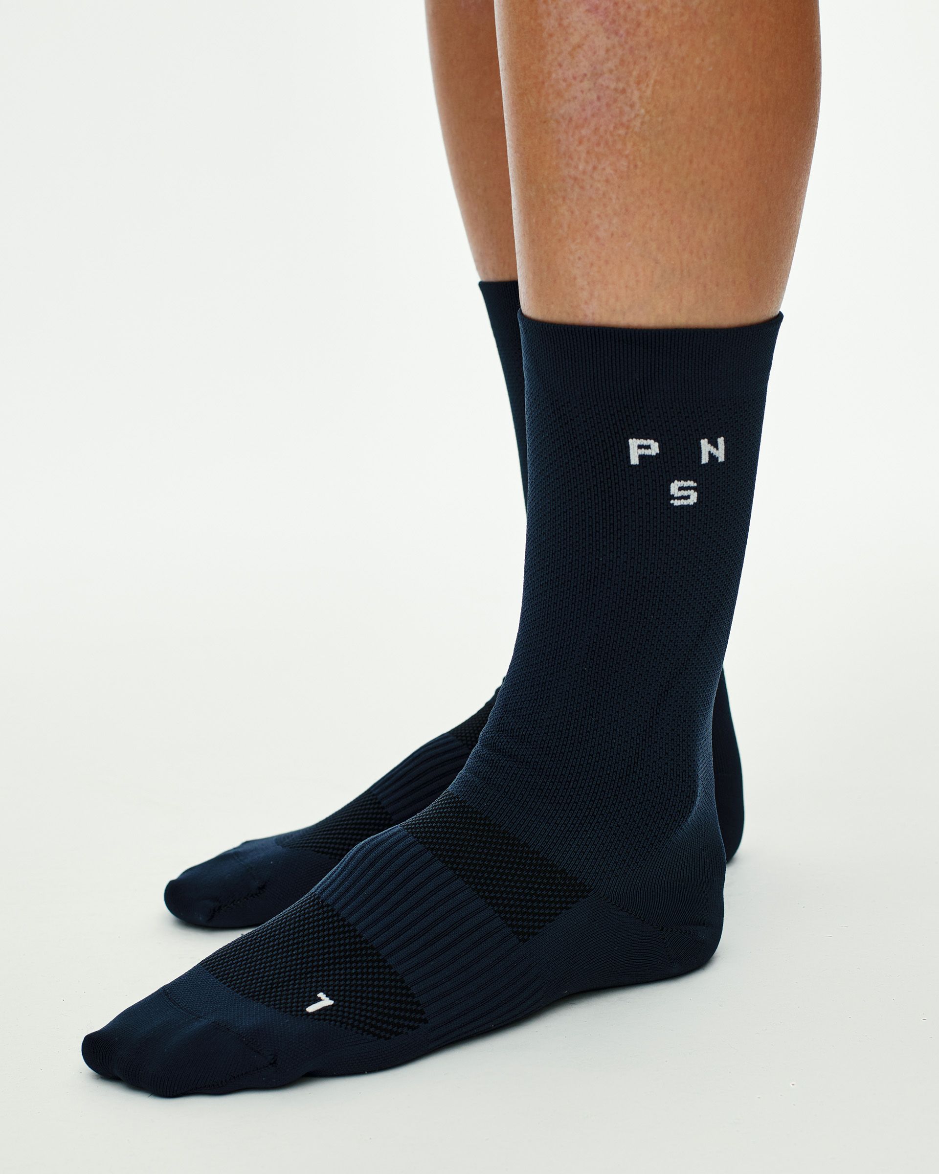 Navy Essential Race cycling socks on model, side view with white logo knit on cuff