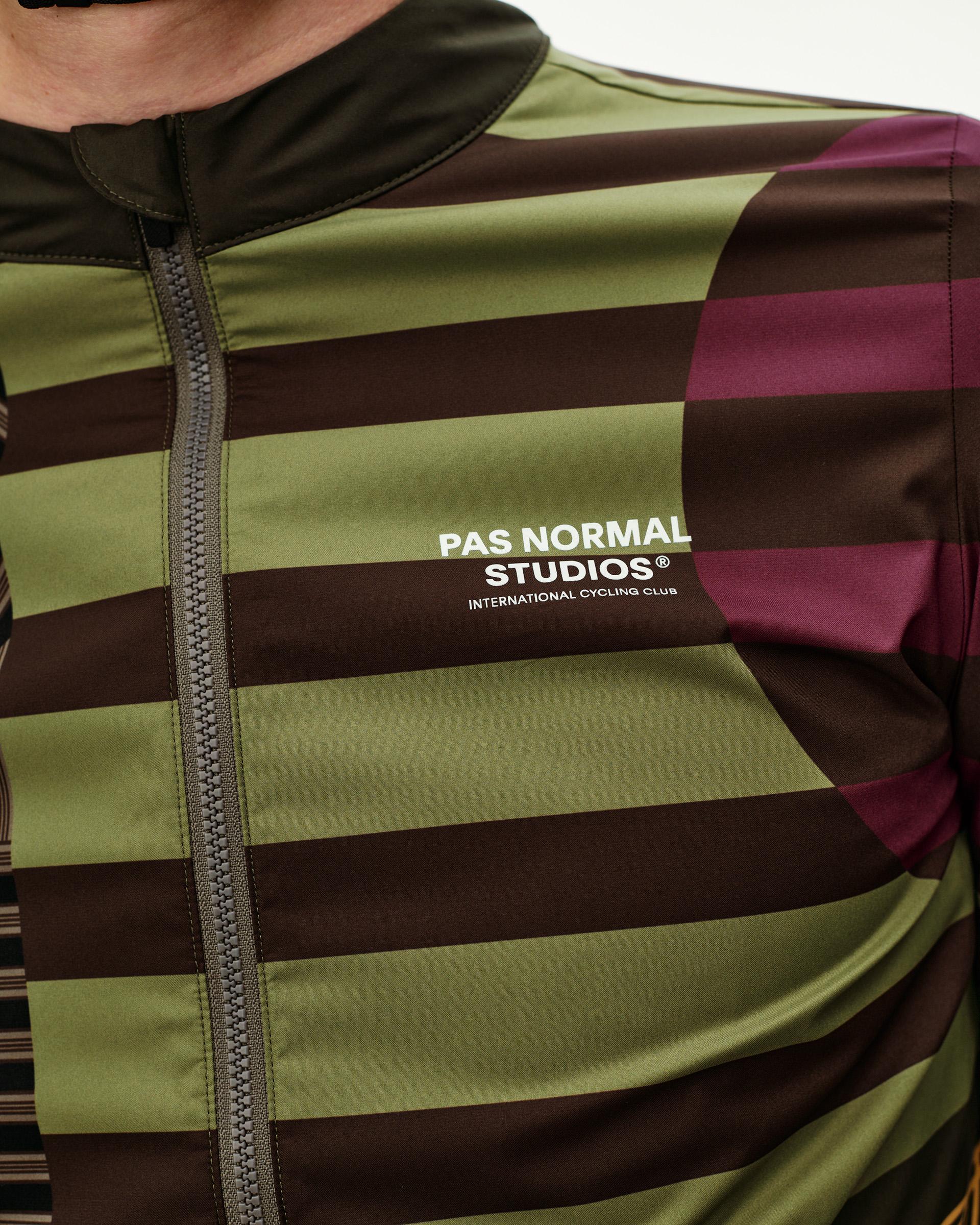 International Green Mechanism Stow Away cycling jacket, front detail on model with olive and brown stripe print