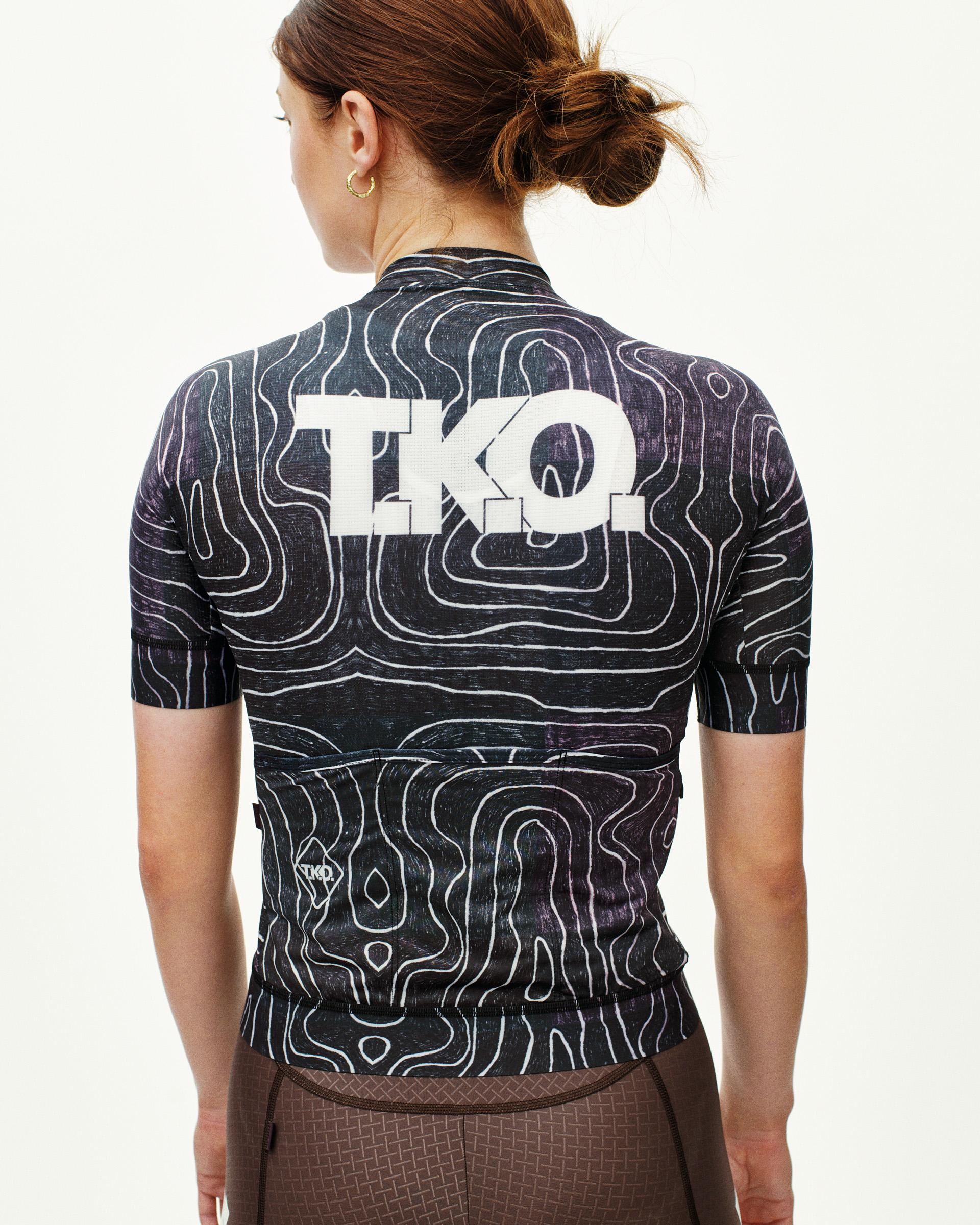Black T.K.O. Mechanism cycling jersey on model, rear view with topographic line print and white back logo