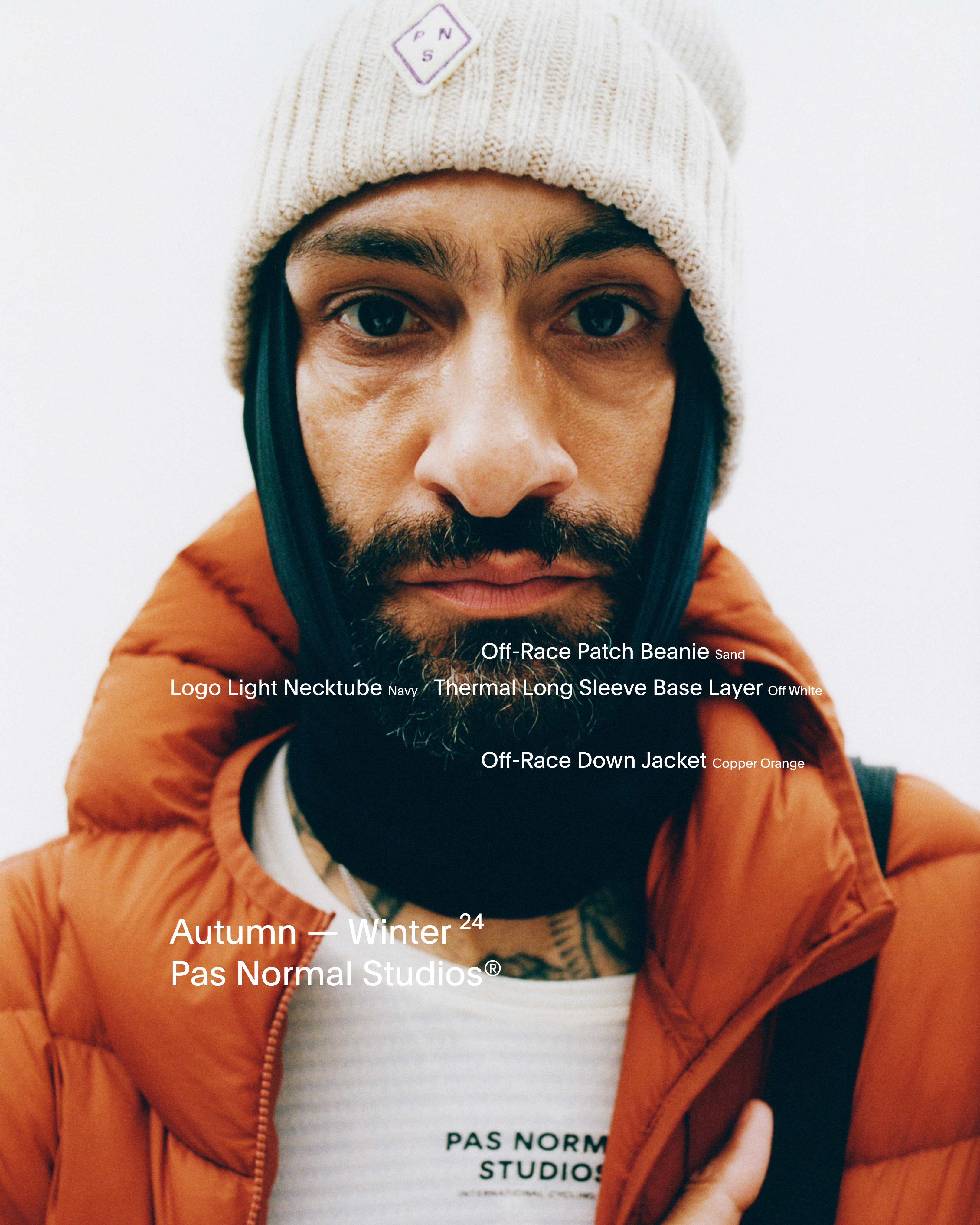 Model wearing Off-Race Patch Beanie in sand, Logo Light Necktube in navy, and Off-Race Down Jacket in orange