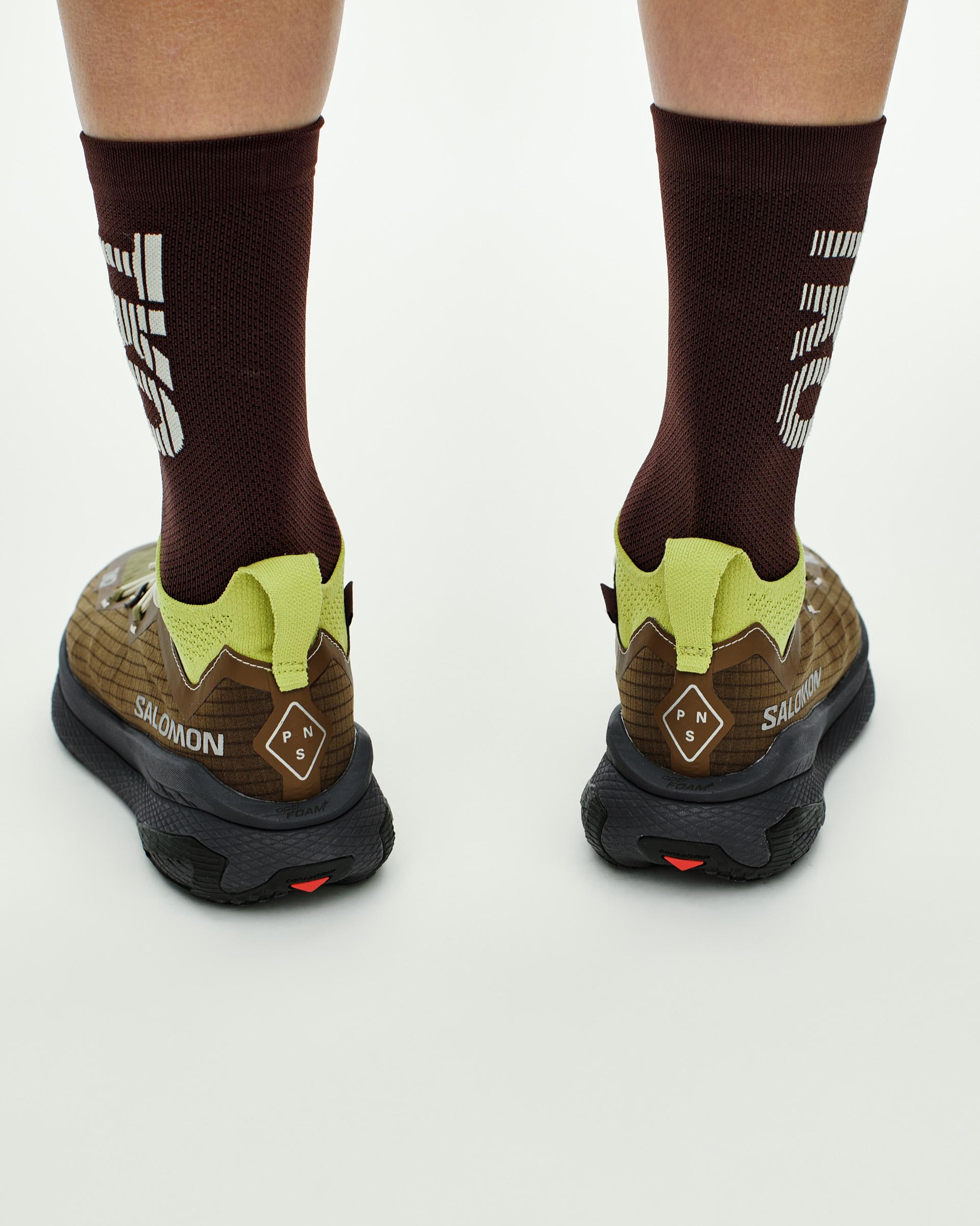 Green Salomon GRVL CONCEPT trail running shoes on model, rear view with brown uppers and lime accents