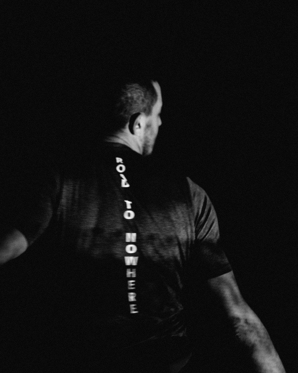 Model wearing black cycling jersey with vertical text down the back, shot in black and white