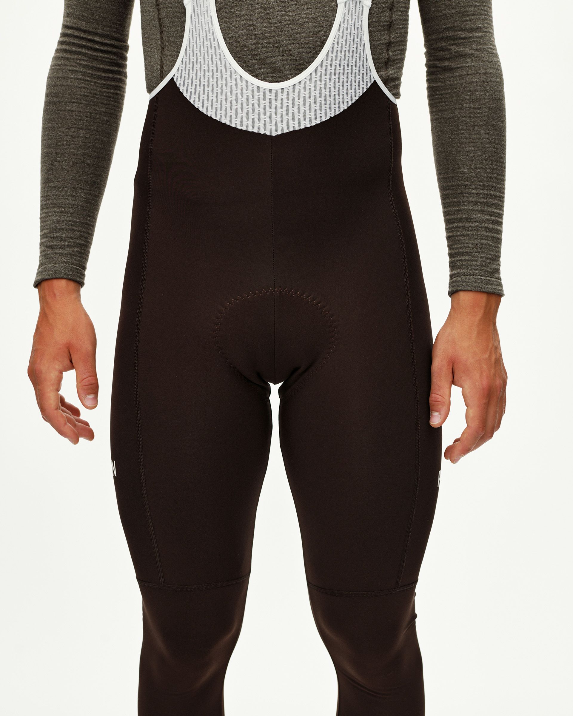 Dark Coffee brown Mechanism Thermal Long cycling bibs on model, front view with white mesh bib straps
