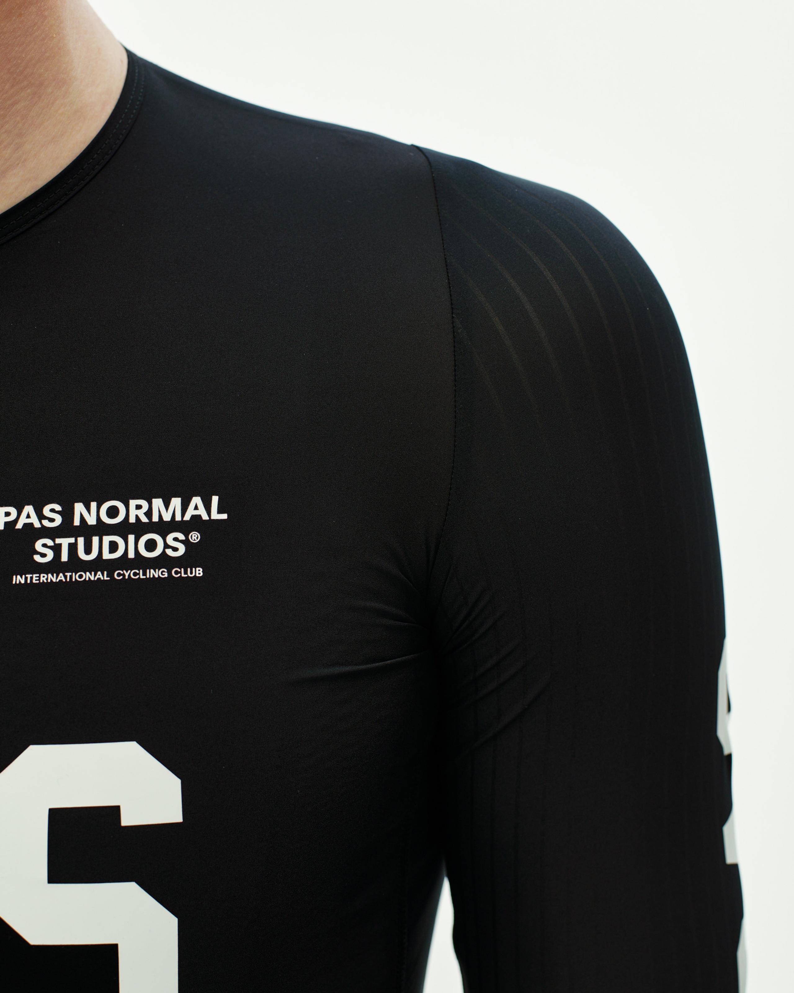 Black PAS Mechanism Pro cycling jersey on model with white chest print and textured shoulder panels
