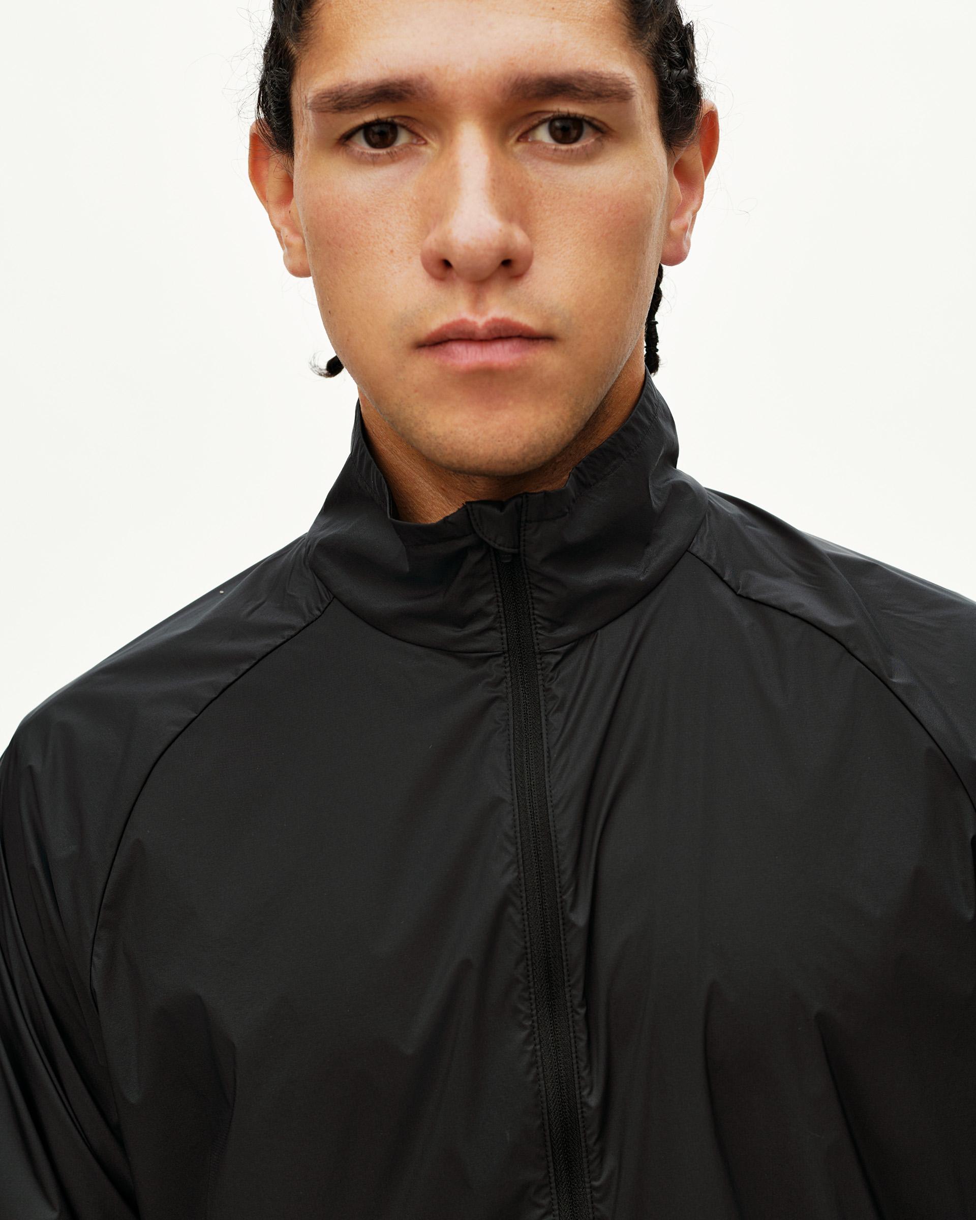 Black Balance Windproof jacket on model, front detail view with high collar and full zip