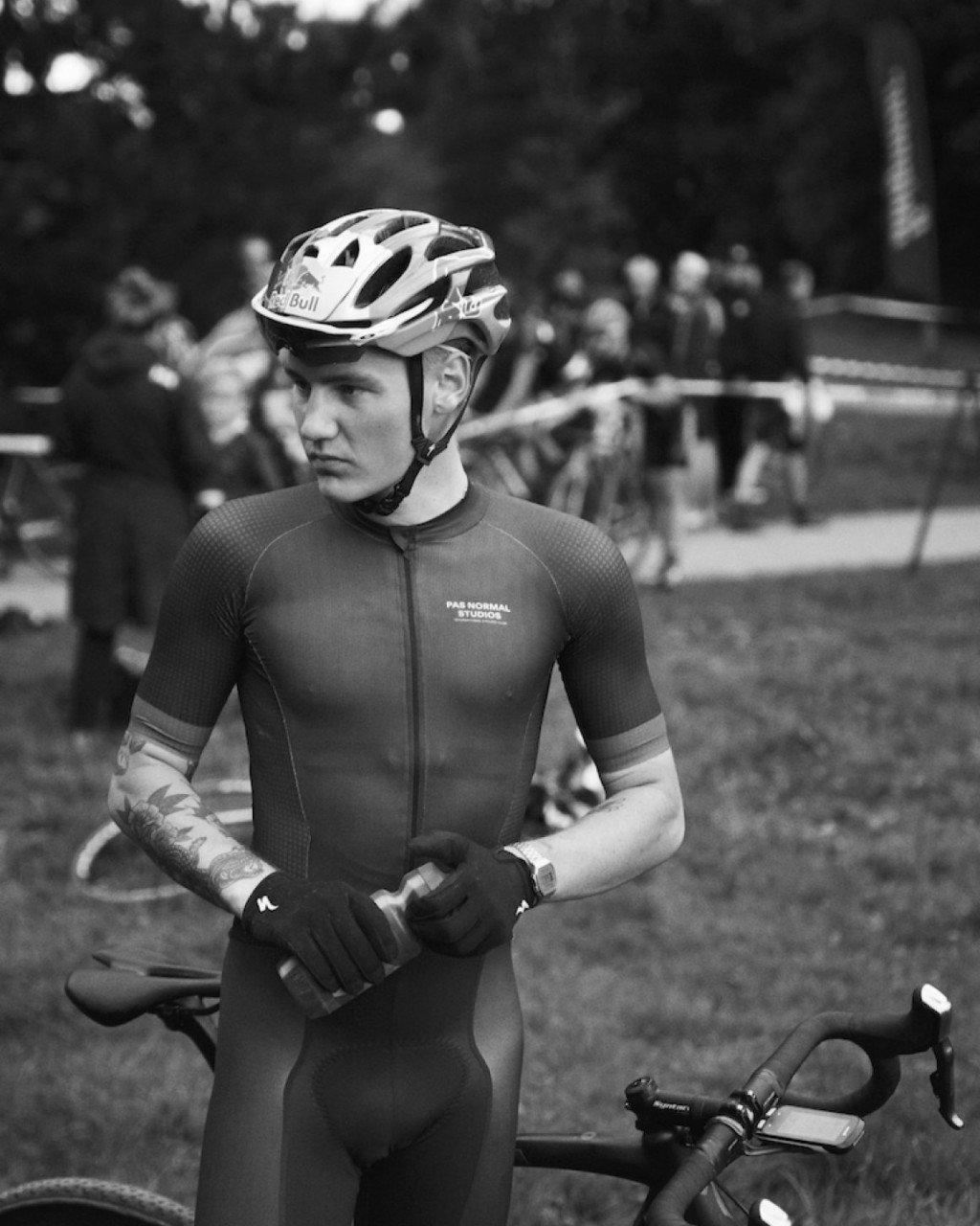 Model wearing cycling skinsuit with chest logo and helmet at outdoor cycling event