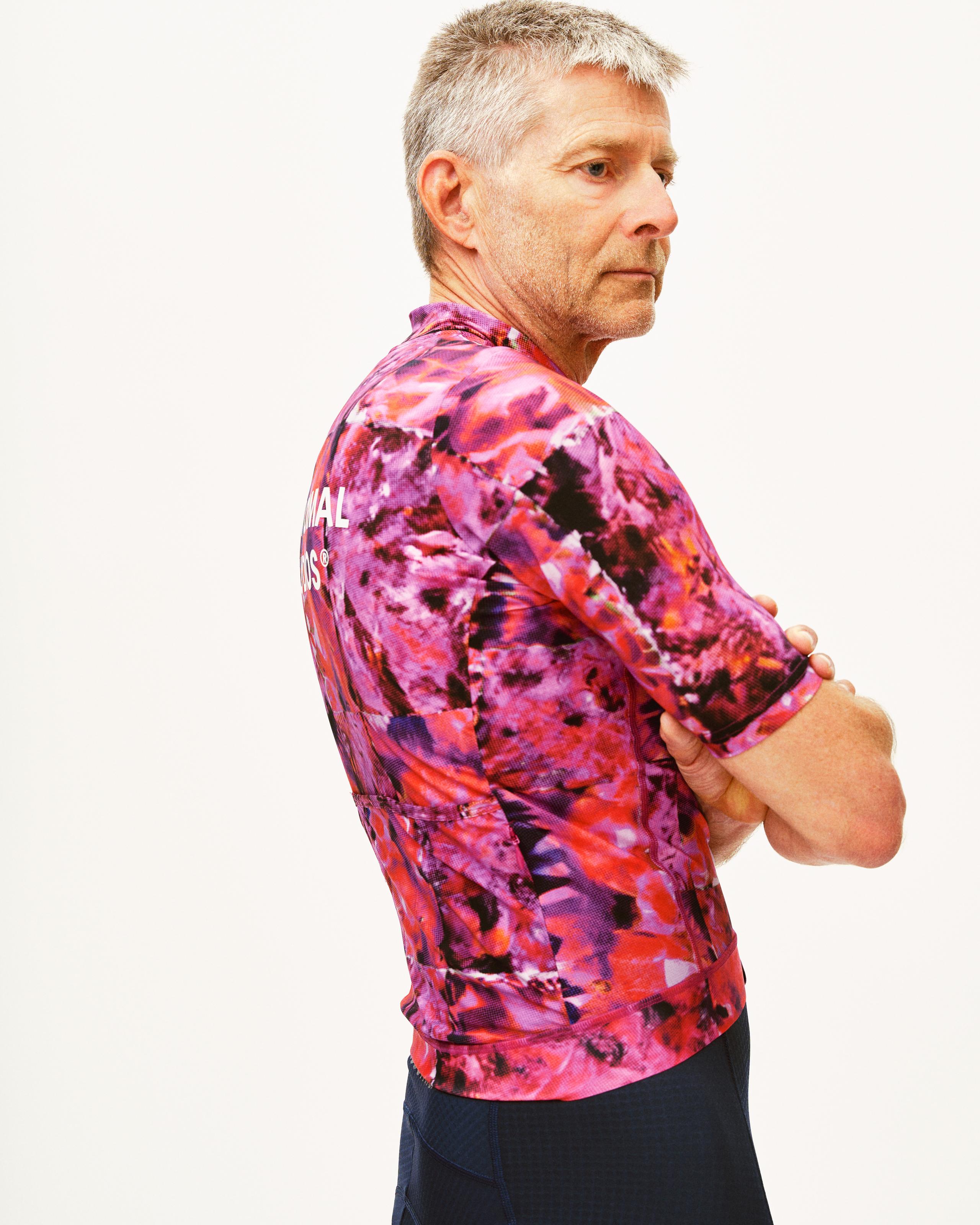 Pink Essential cycling jersey on model, side view with abstract kaleidoscope print