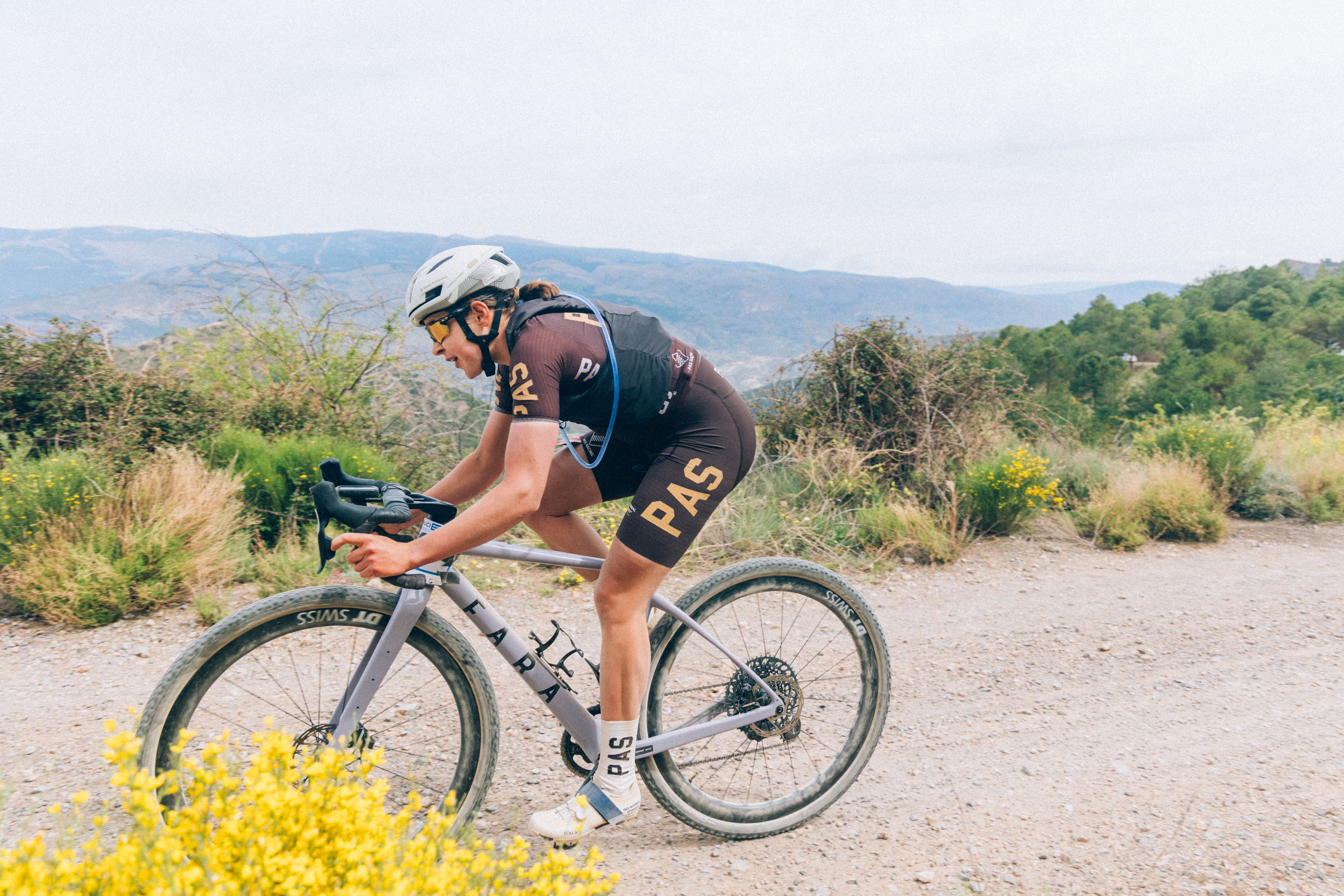 Model wearing PAS Racing triathlon suit in aero position on gravel bike in mountainous terrain