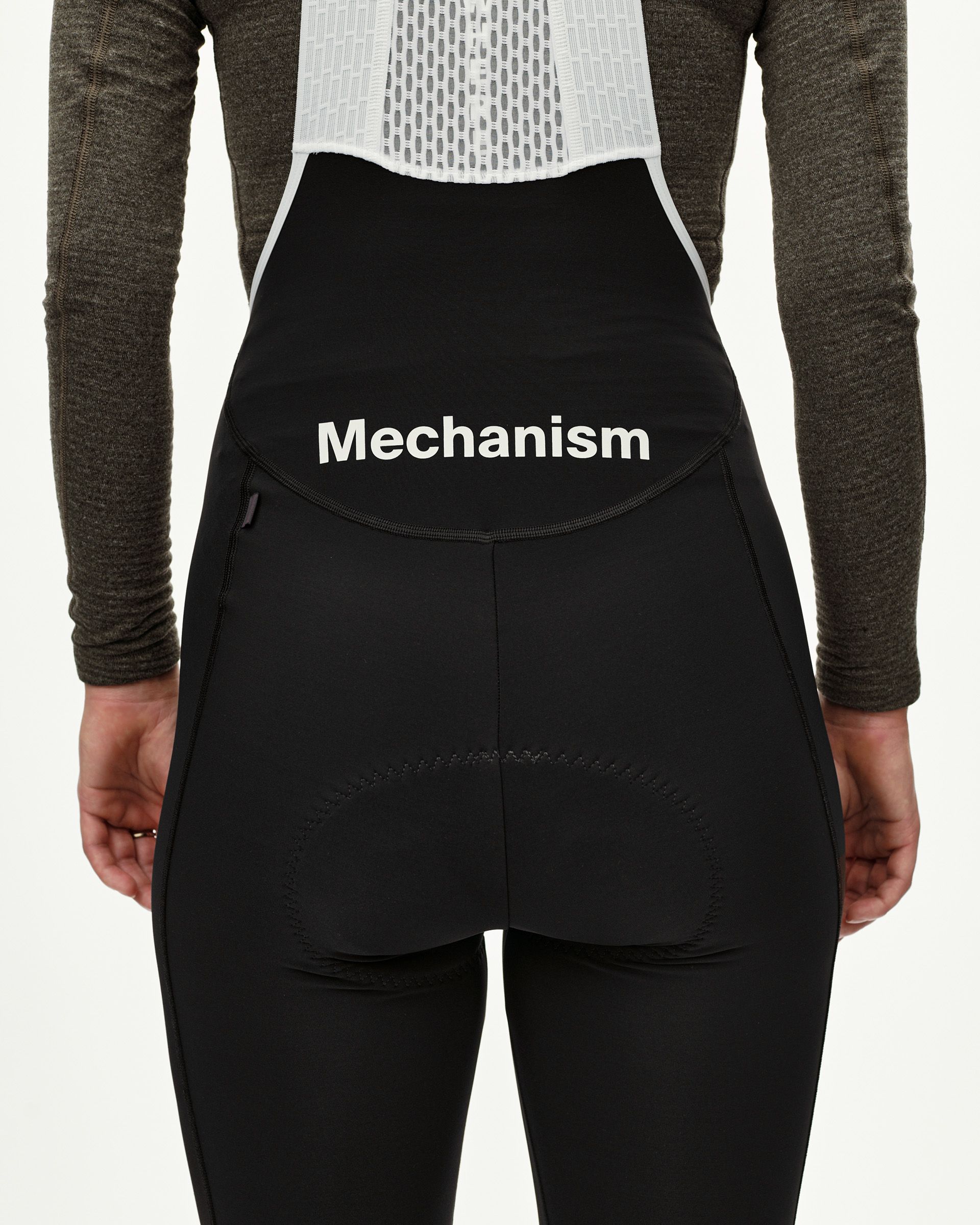 Black Mechanism women's thermal cycling long bibs, rear view on model with white logo waistband print