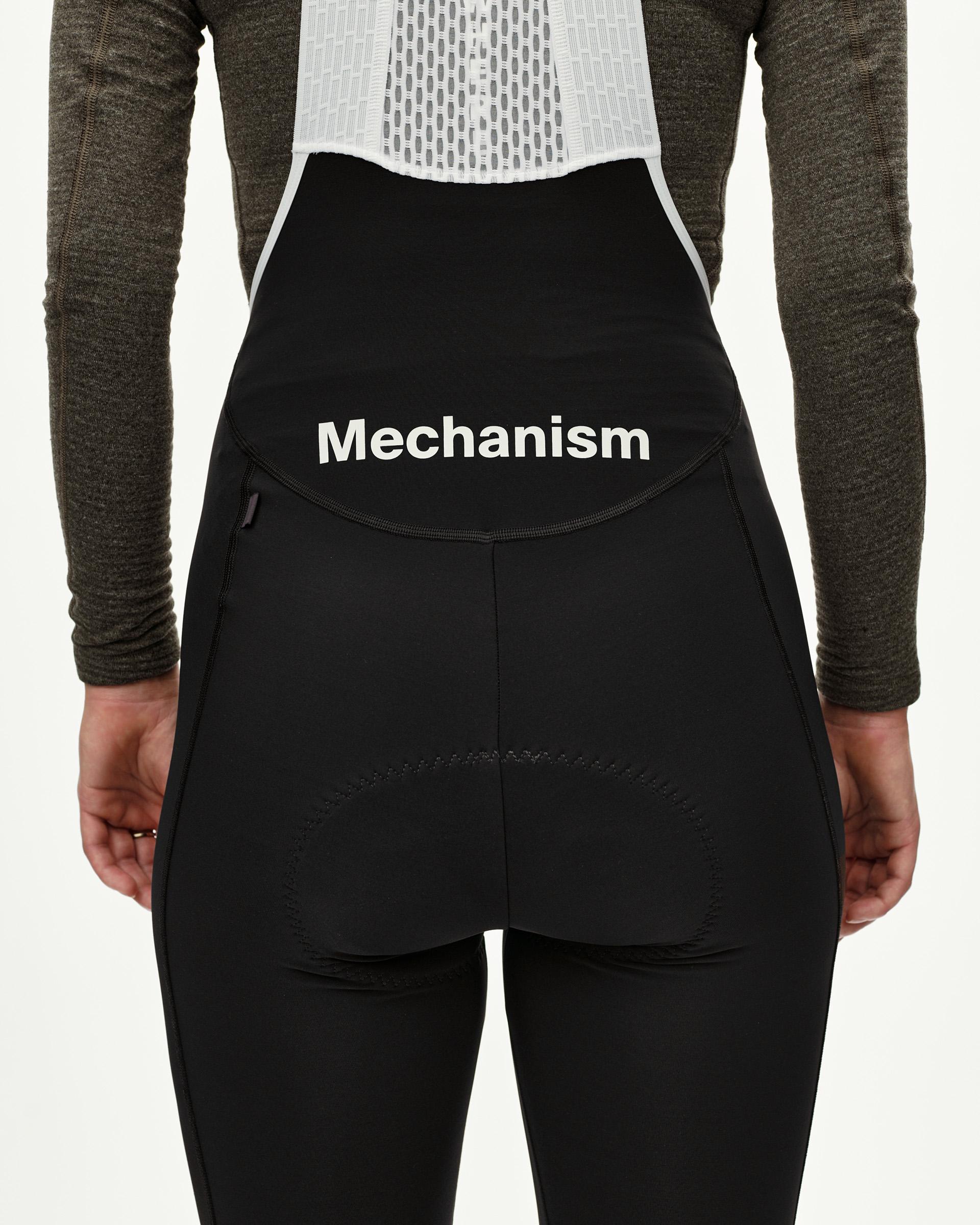 Black Mechanism women's thermal cycling long bibs, rear view on model with white logo waistband print