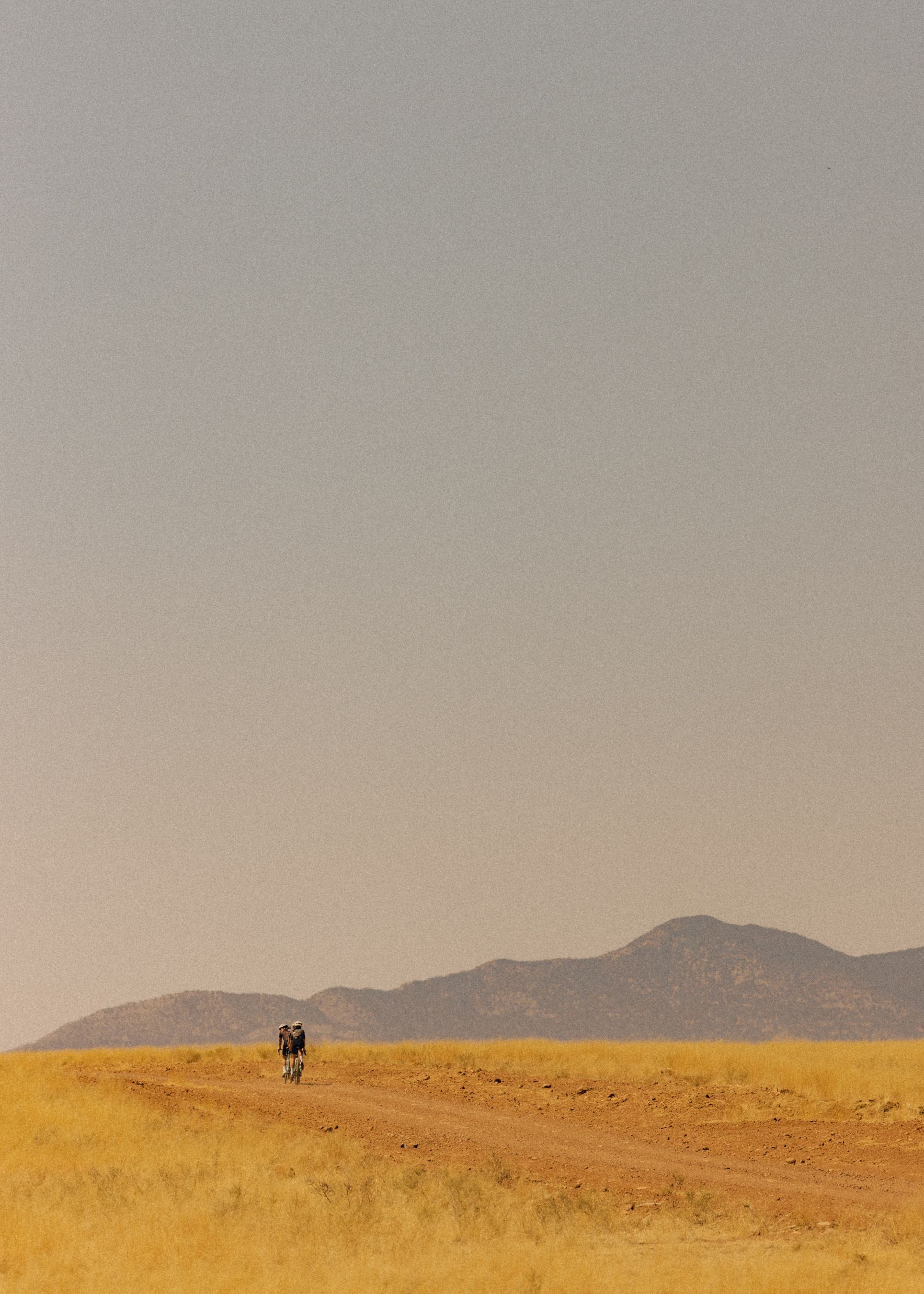 Cyclist riding through desert landscape with mountains in background