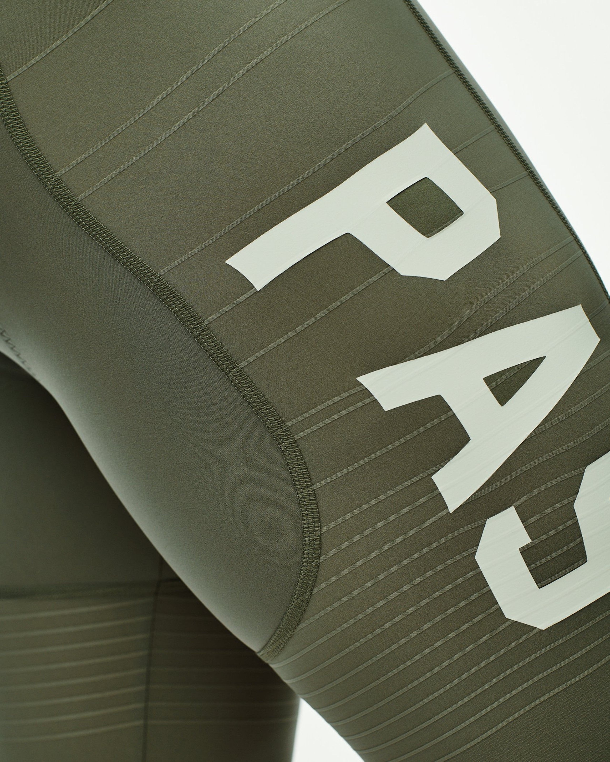 Green PAS Mechanism Pro cycling bibs, detail view with white PAS logo on ribbed leg panel