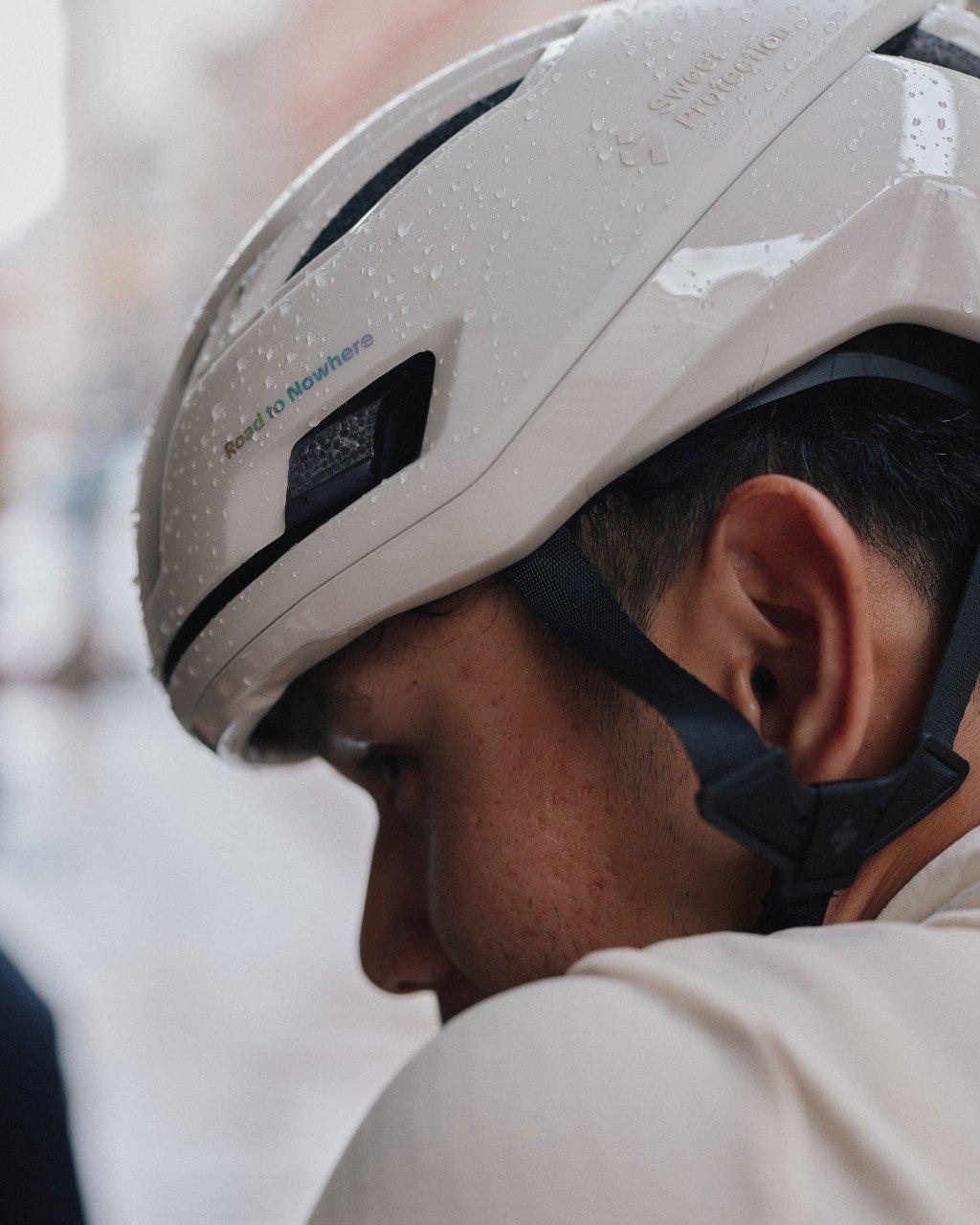 Cyclist wearing white aerodynamic helmet with water droplets and blue lettering