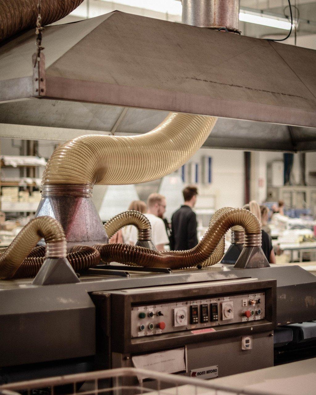 Industrial textile machinery with flexible hoses in manufacturing facility