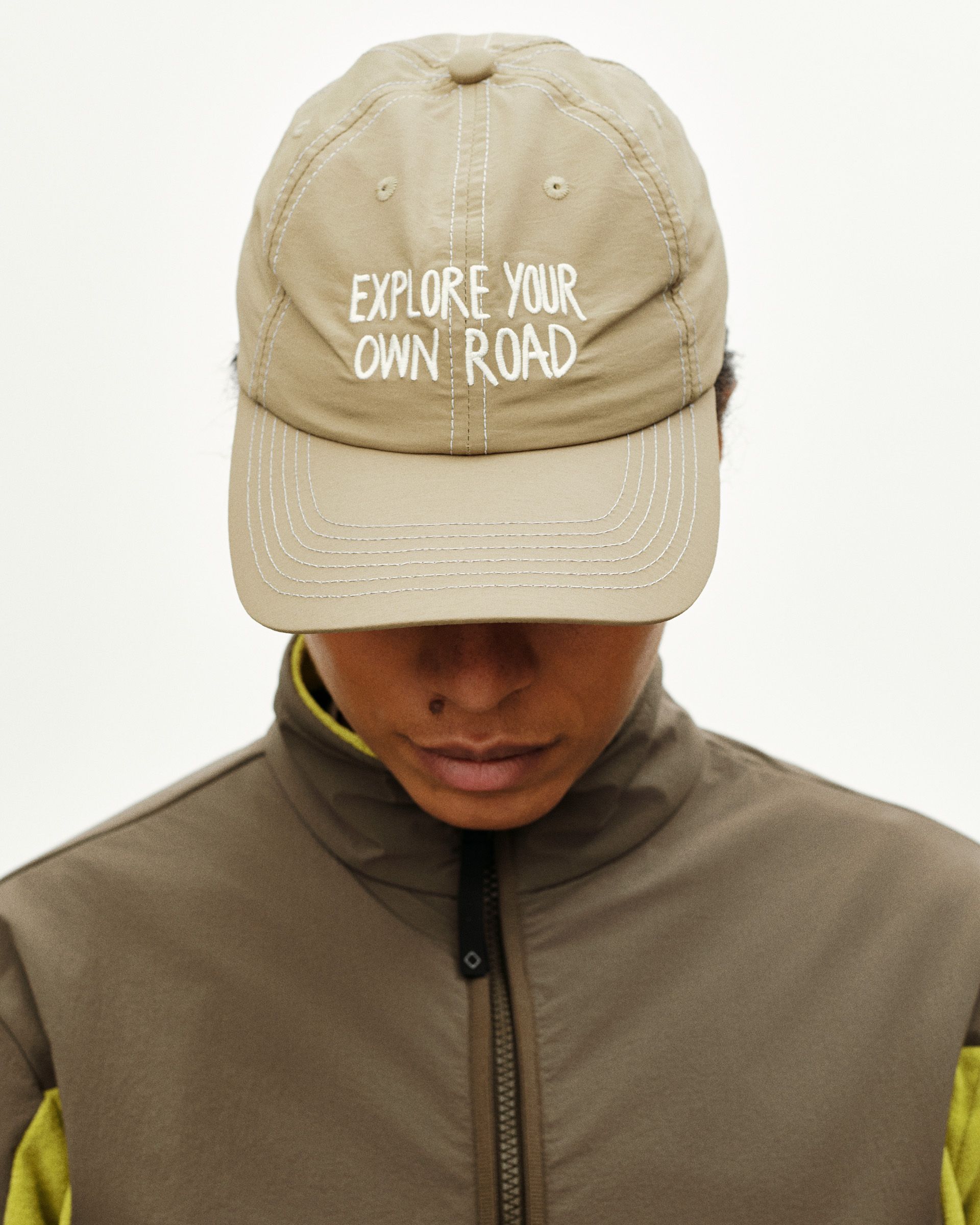 Beige Off-Race cap on model with white "EXPLORE YOUR OWN ROAD" text
