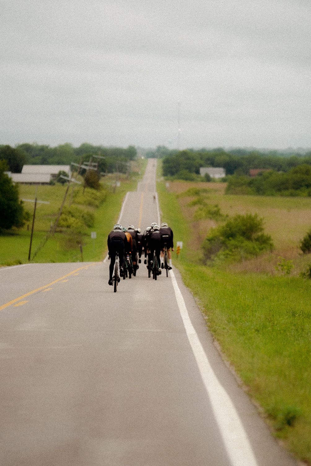 Group of cyclists riding in formation on rural road through countryside