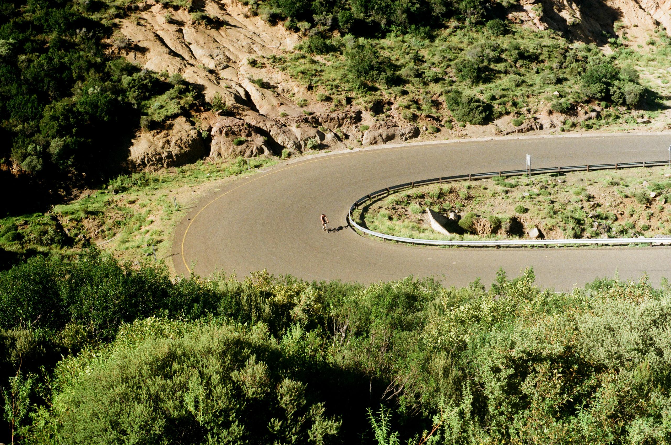 Cyclist on winding mountain road through green landscape in Lesotho