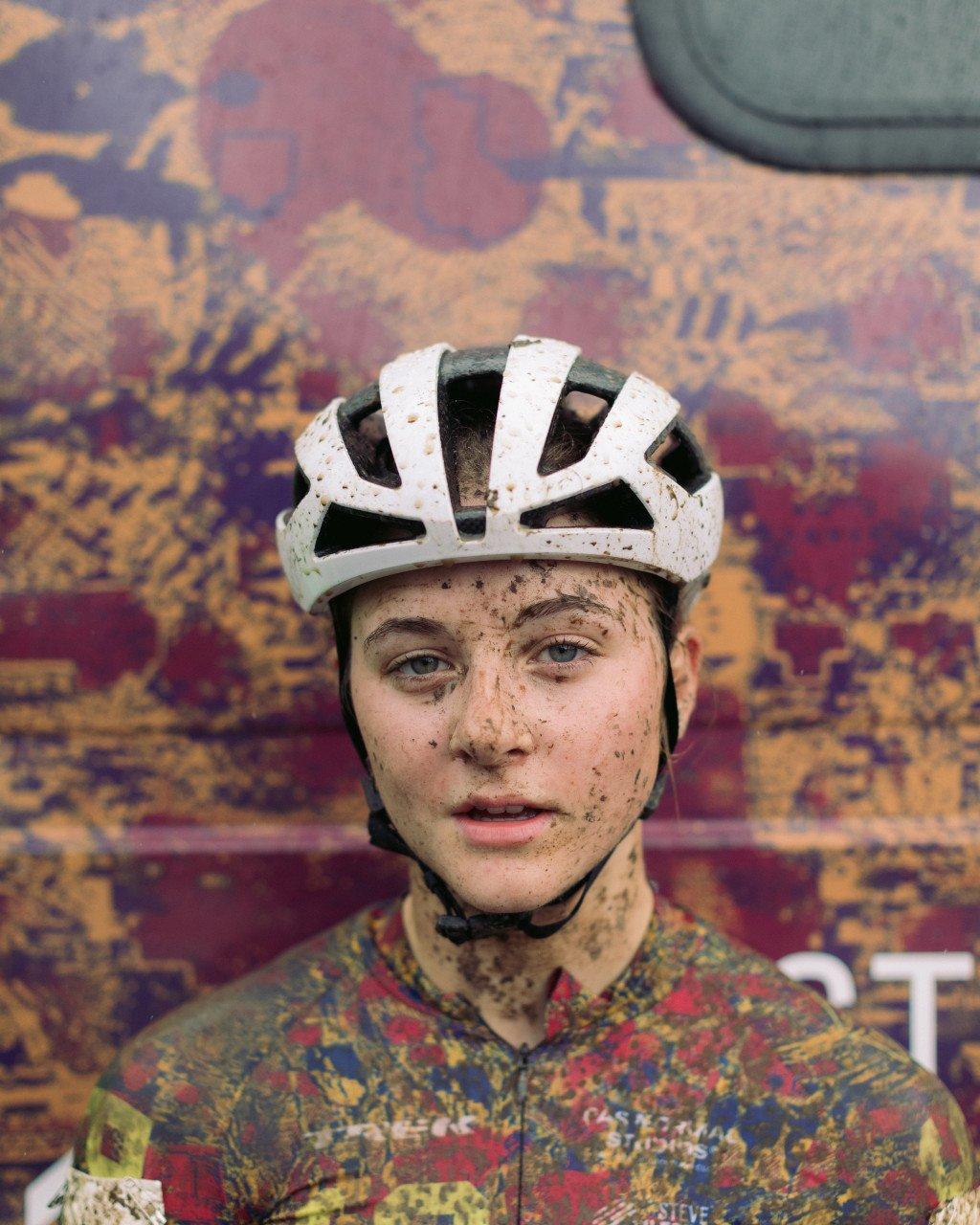 Model wearing muddy white cycling helmet and colorful jersey after cyclocross race