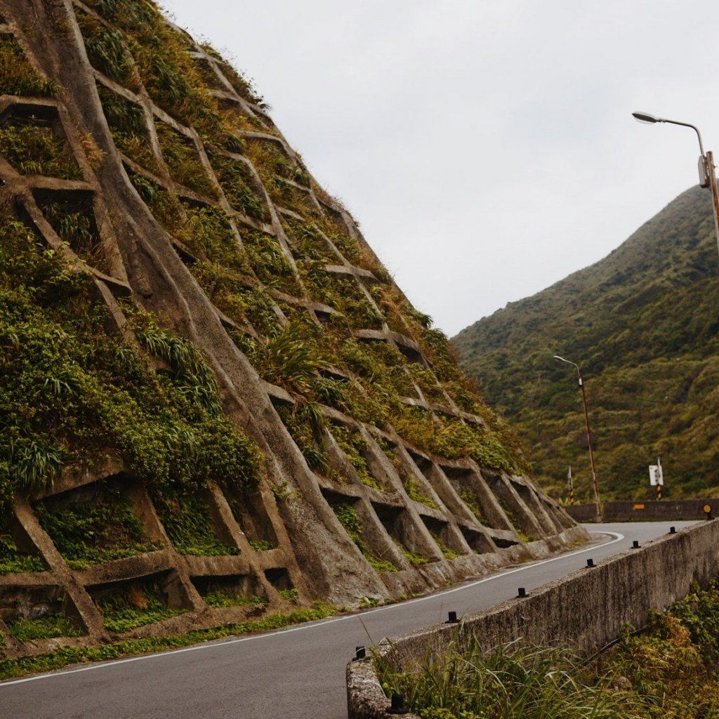 Mountain road with concrete retaining wall and lush green hillside