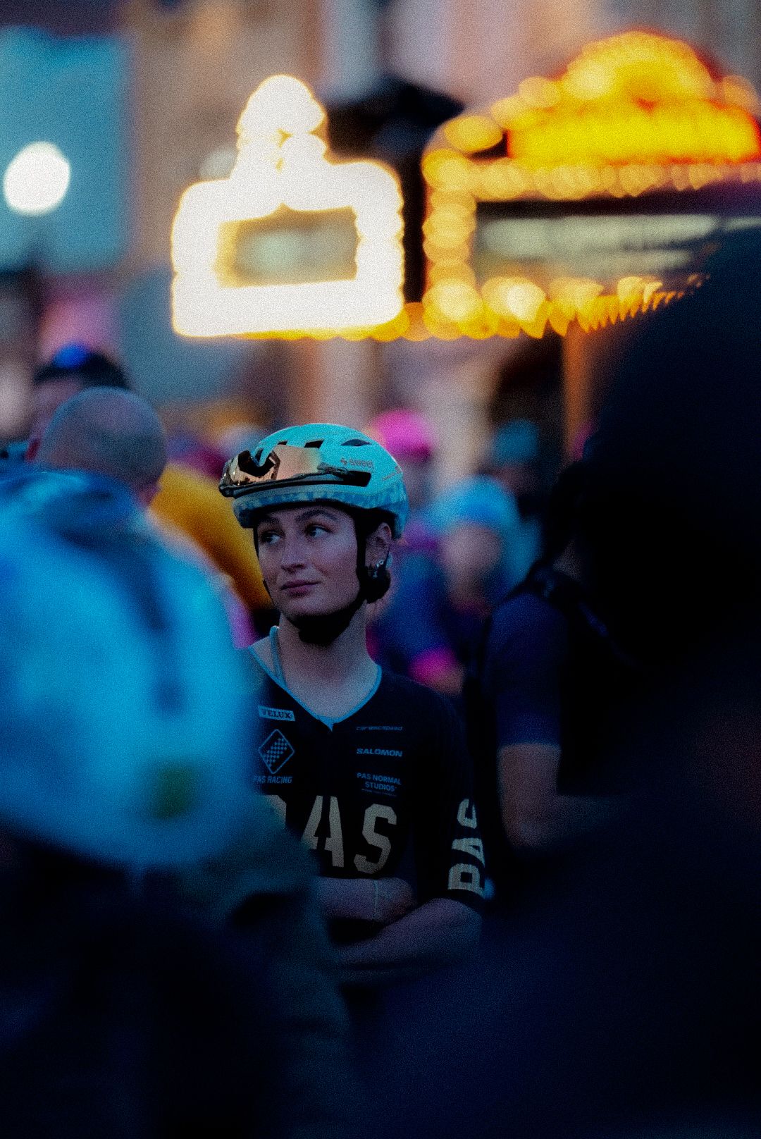 Model wearing blue cycling helmet and dark jersey with logo in evening urban setting