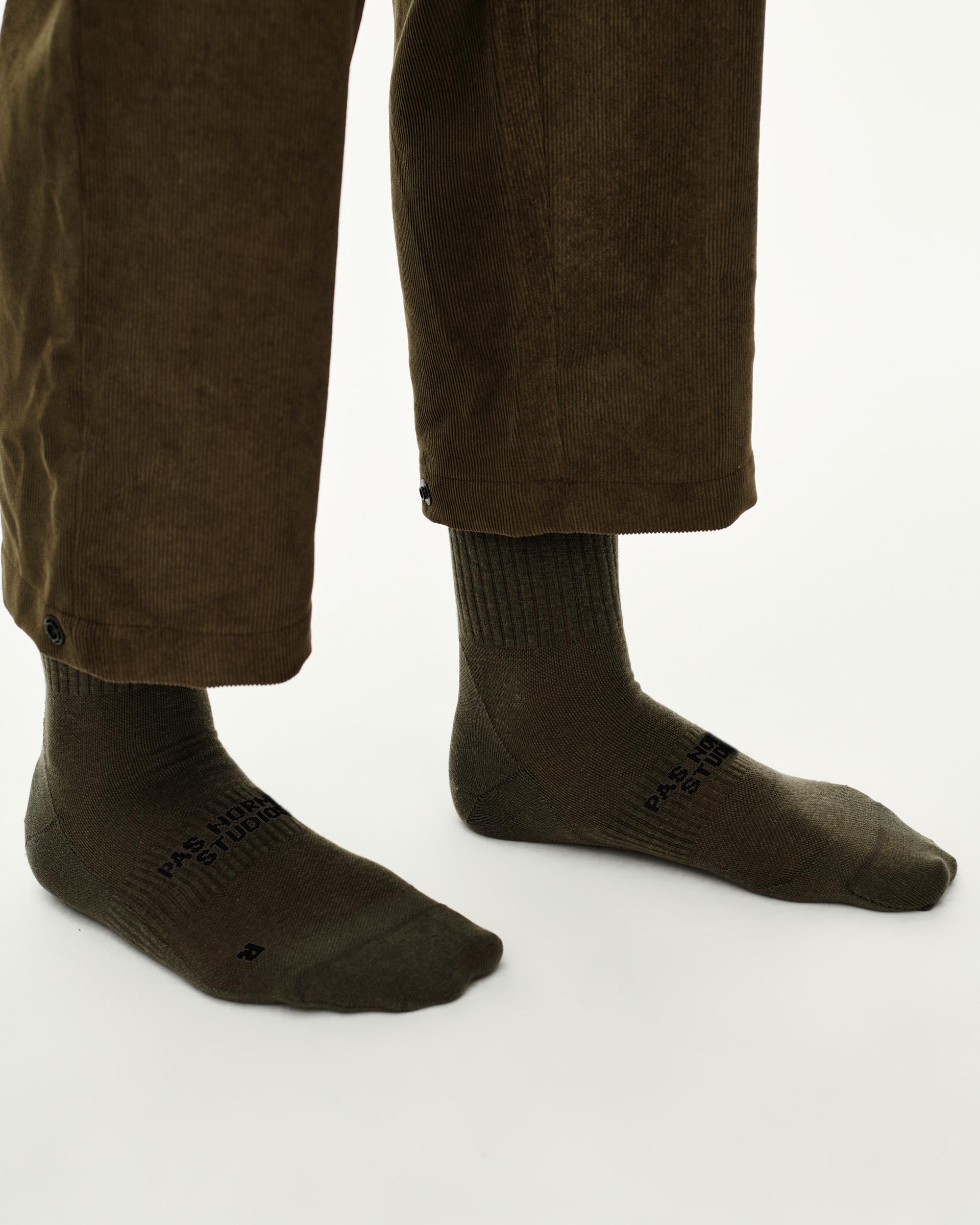 Grey Green Off-Race socks on model, side view pair with black logo print on foot