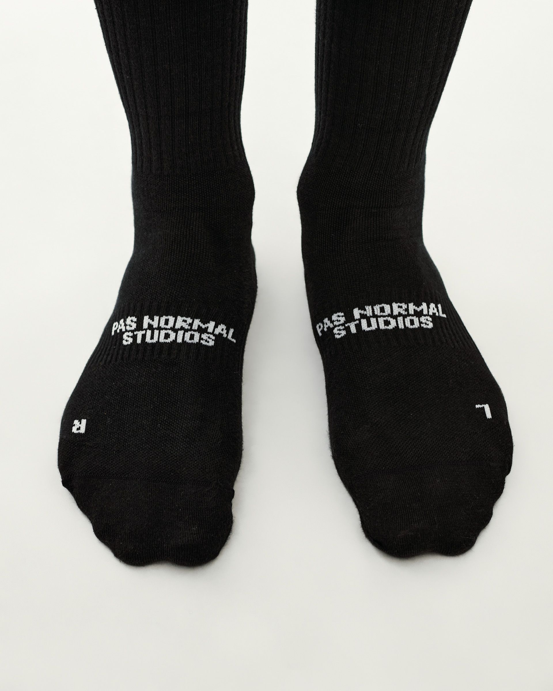 Black Off-Race cycling socks, top-down pair on model with white logo on instep