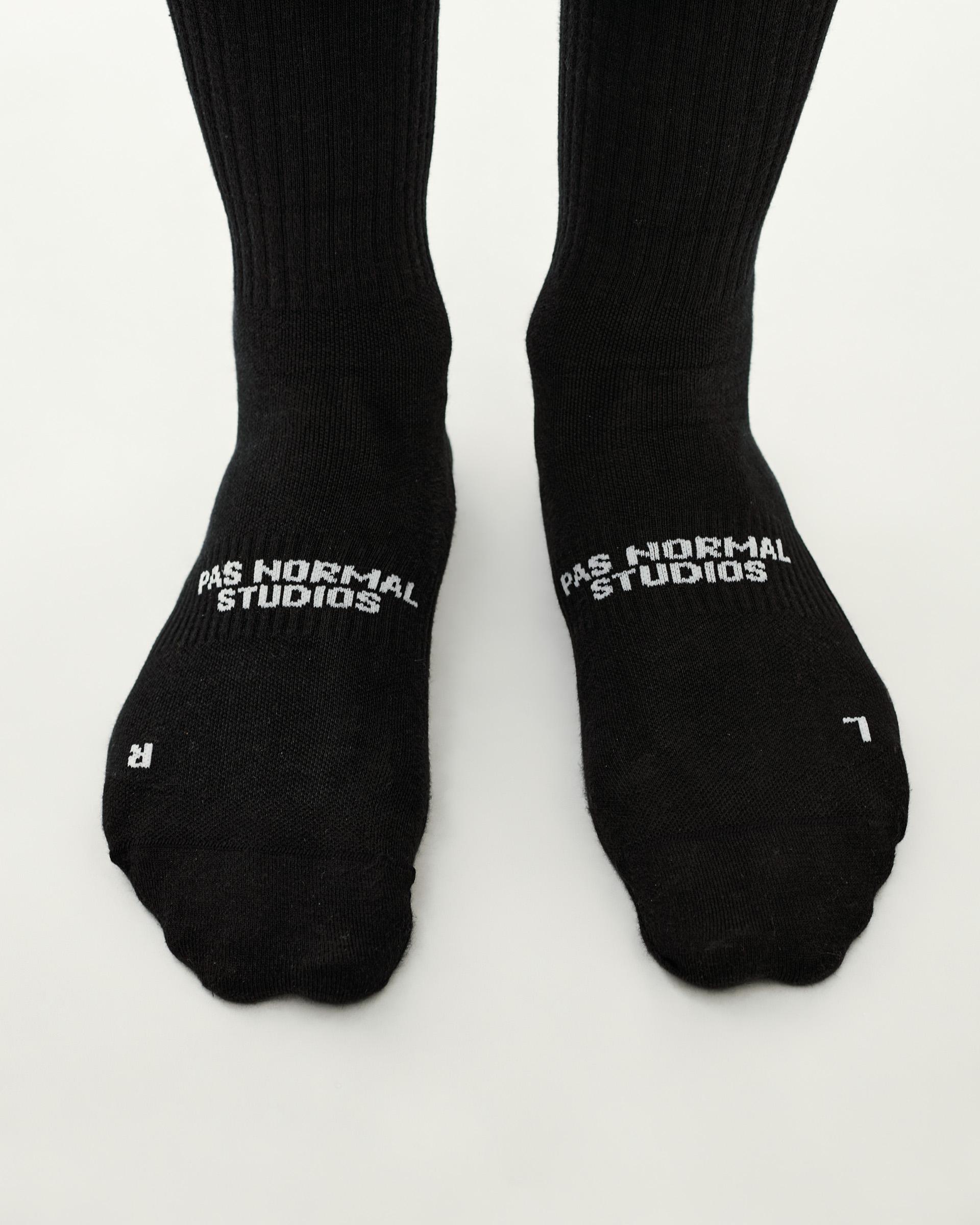 Black Off-Race cycling socks, top-down pair on model with white logo on instep