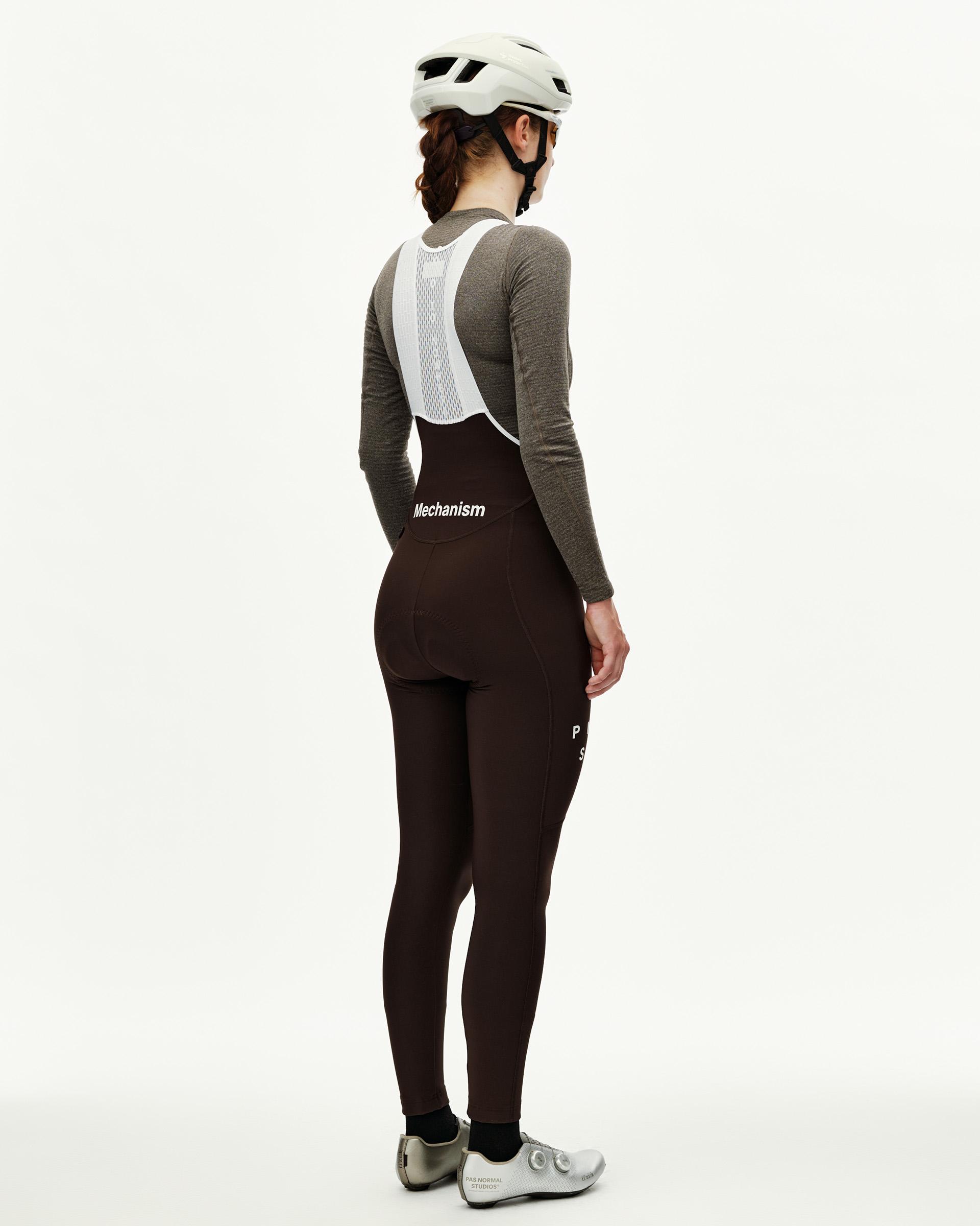 Dark Coffee brown Mechanism women's thermal cycling bib tights on model, rear view with white mesh bib straps