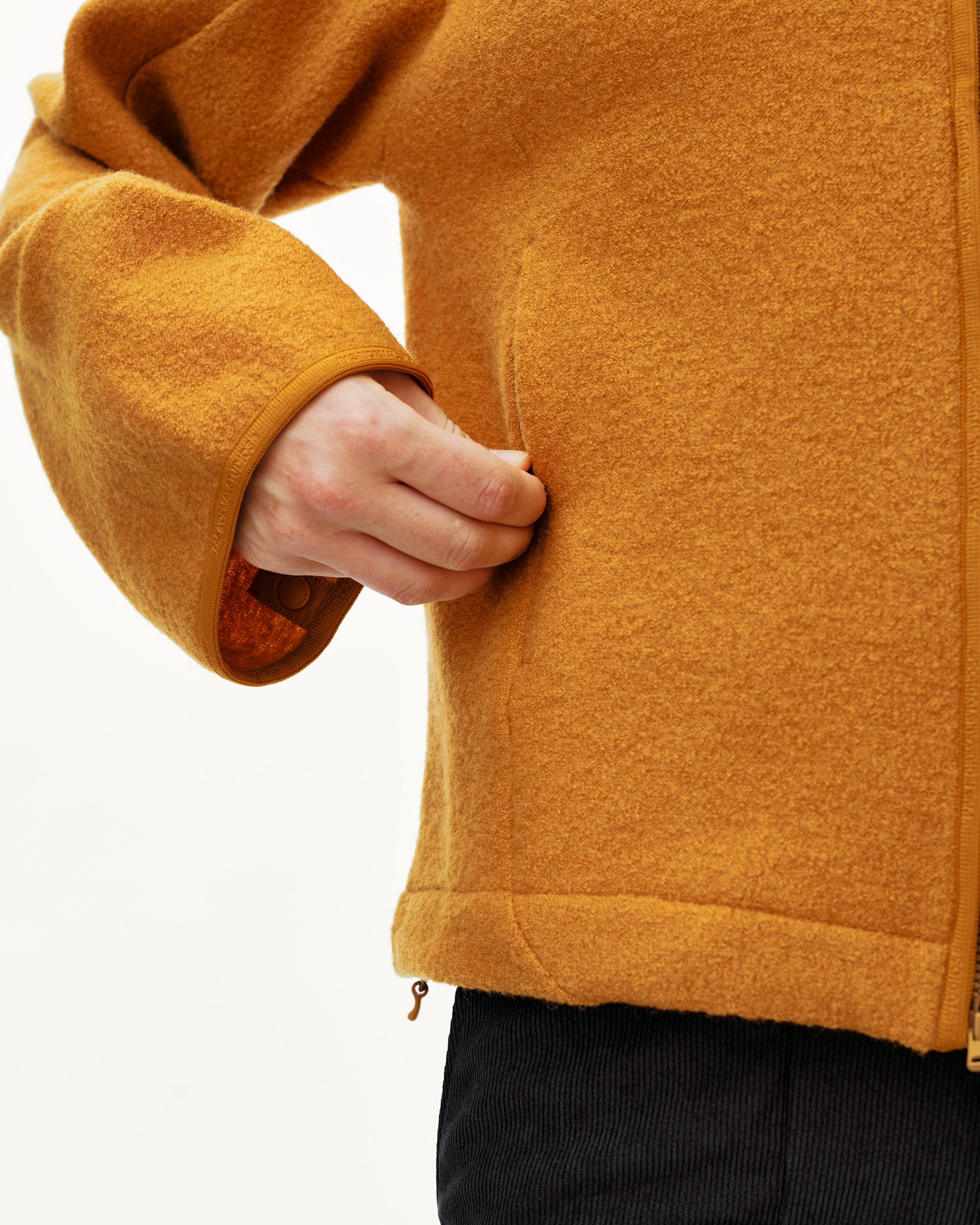 Ochre Off-Race Boiled Wool jacket, detail view of ribbed cuff and side zip pocket on model