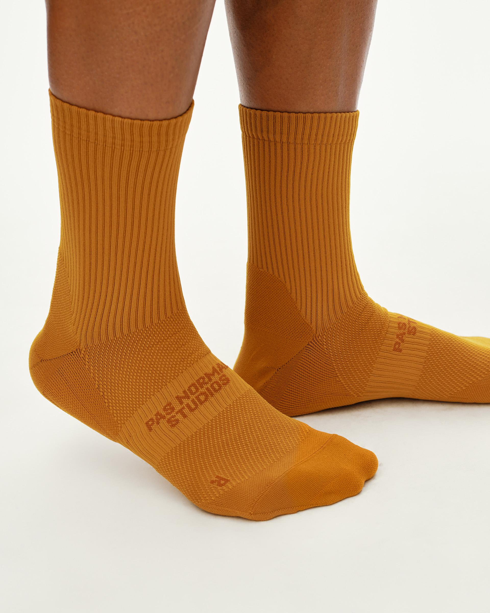 Ochre Balance cycling socks on model, front view with ribbed cuff and tonal logo print
