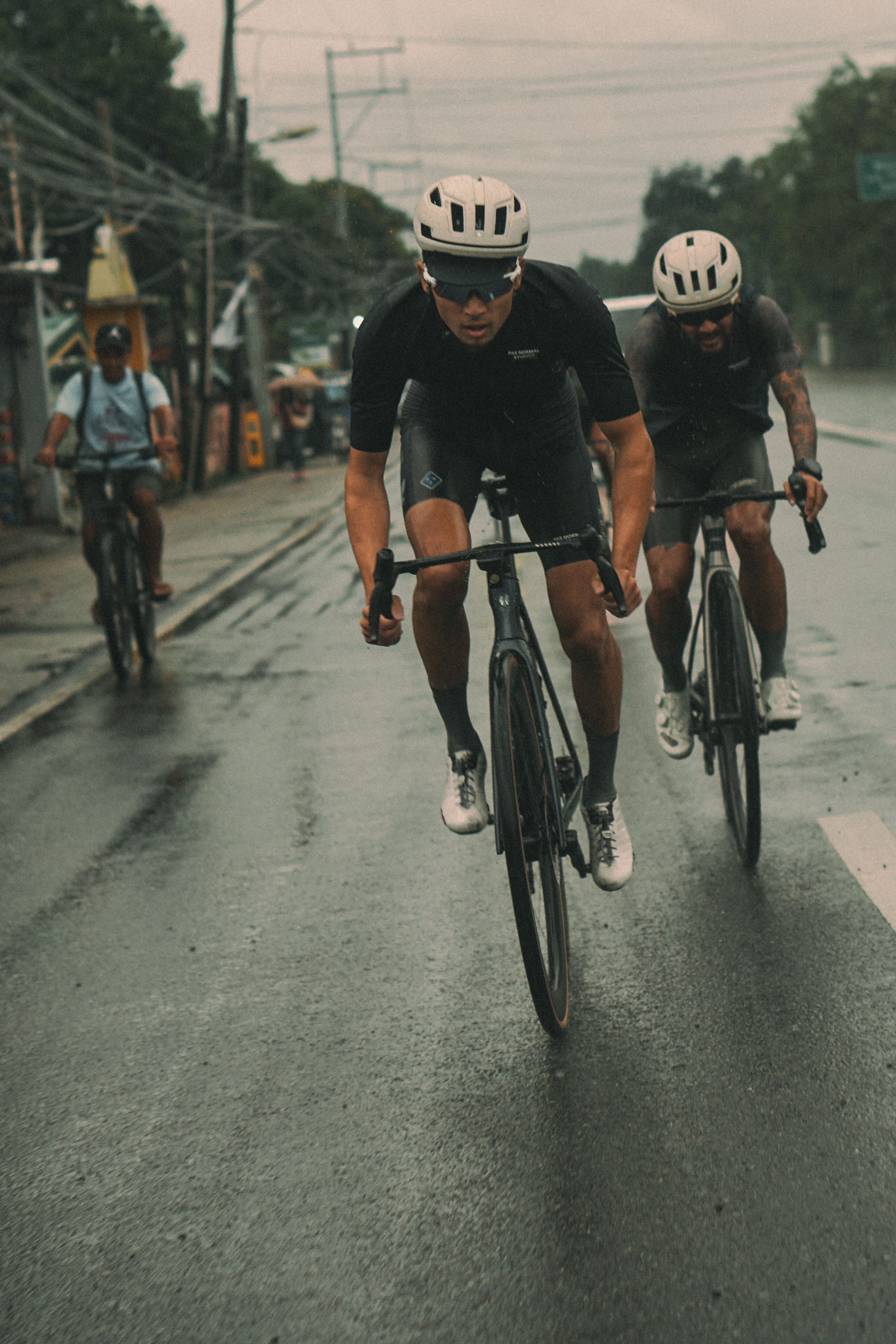 Cyclists in black time trial apparel racing on wet urban road