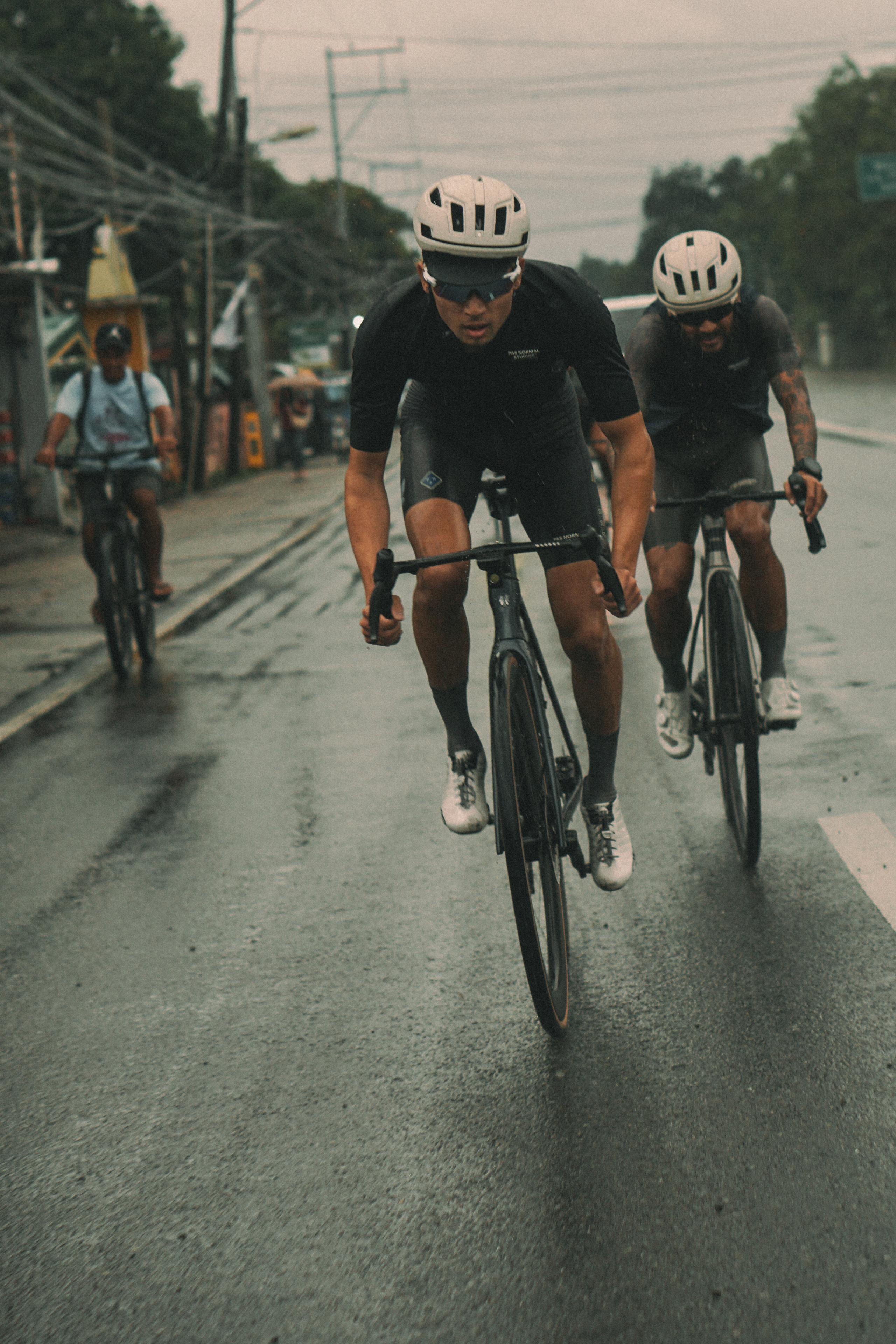 Cyclists in black time trial apparel racing on wet urban road