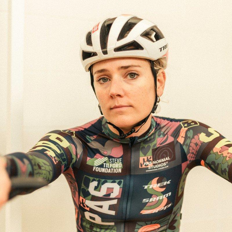 Model wearing multicolored camouflage cycling jersey with white helmet in studio shot