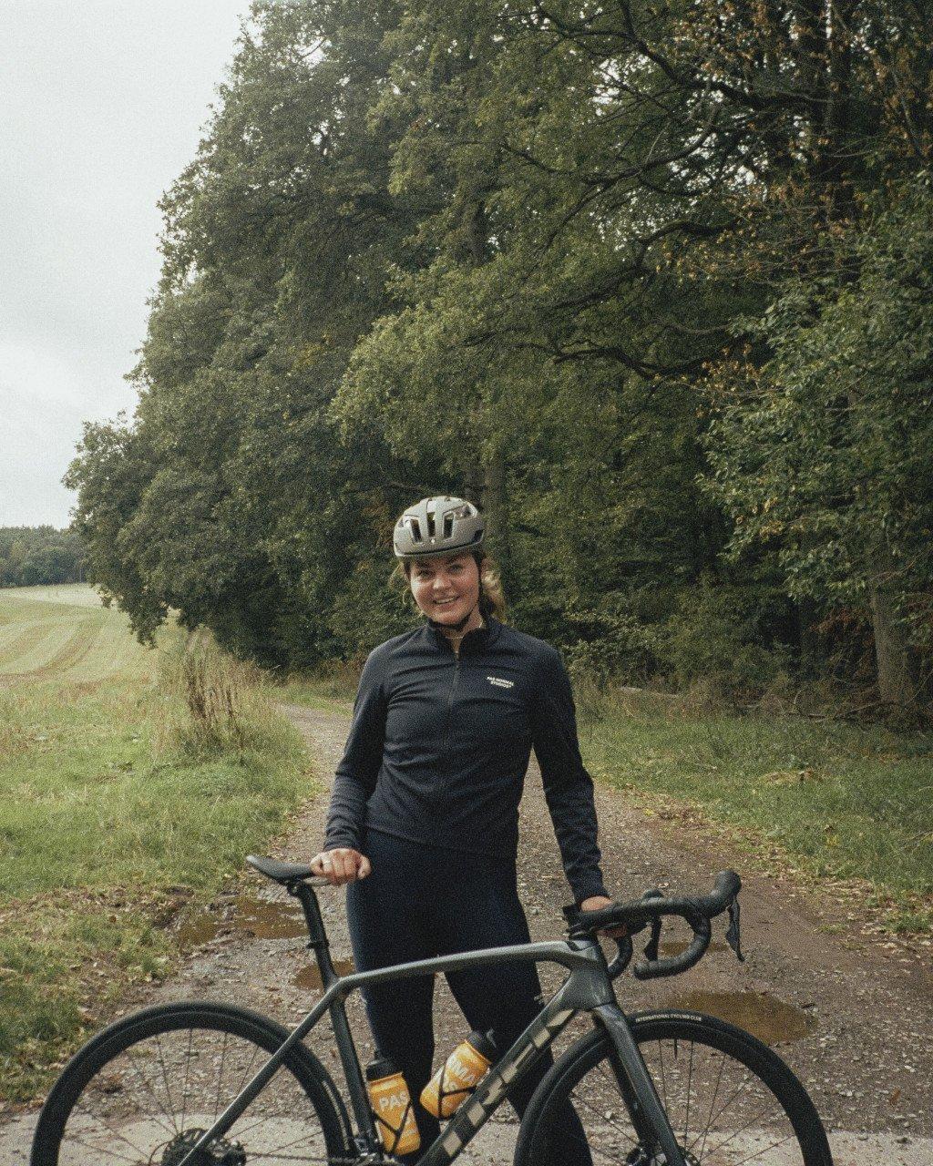 Model wearing black Essential long sleeve jersey with bike on countryside path