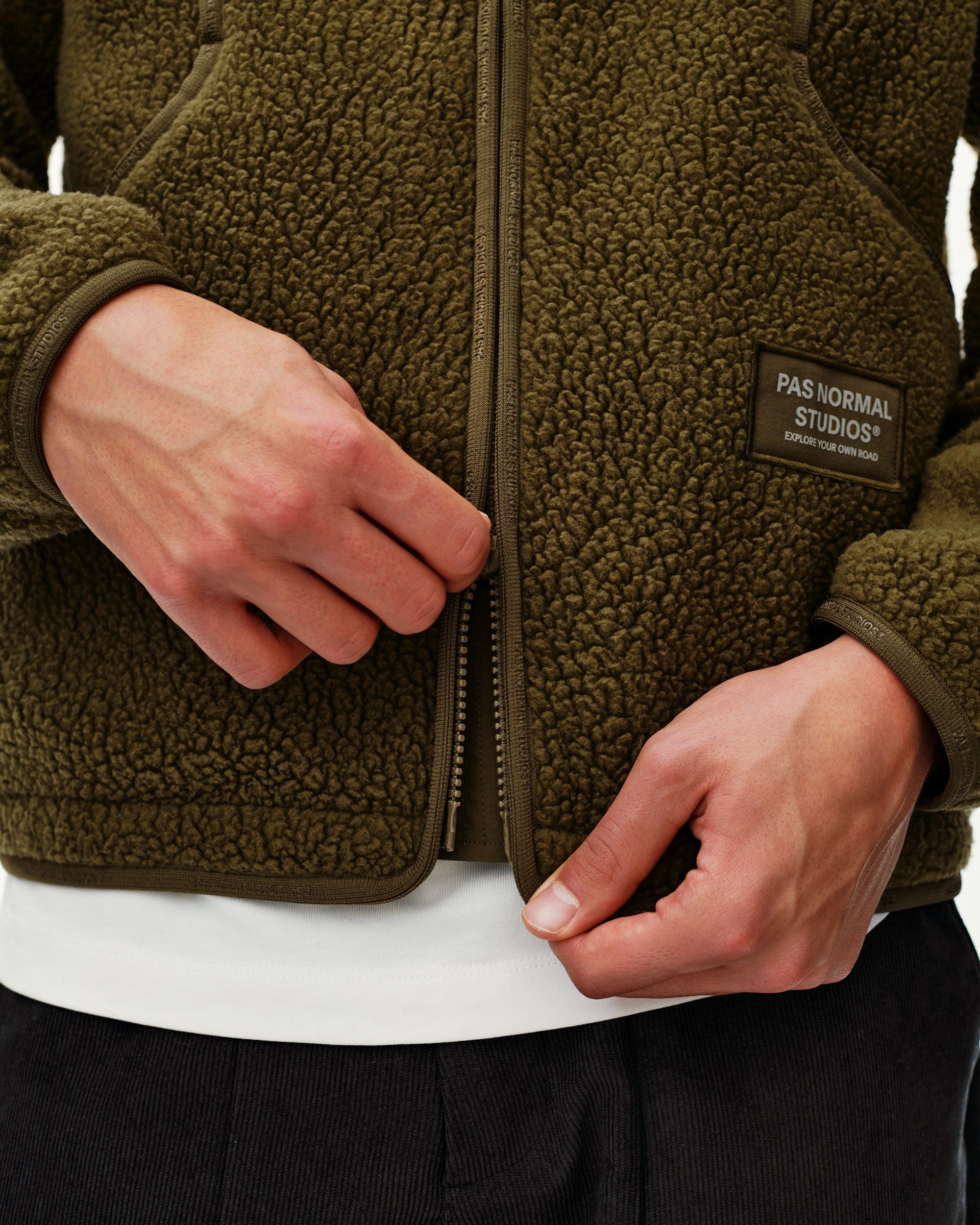 Deep Olive Off-Race Pile Fleece jacket, front detail on model with full zip and branded chest patch