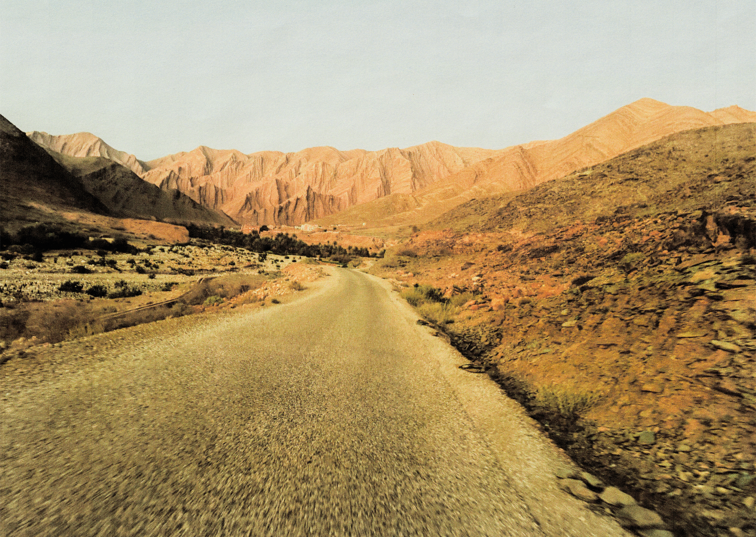 Desert road winding through Atlas Mountains with golden light on rocky terrain