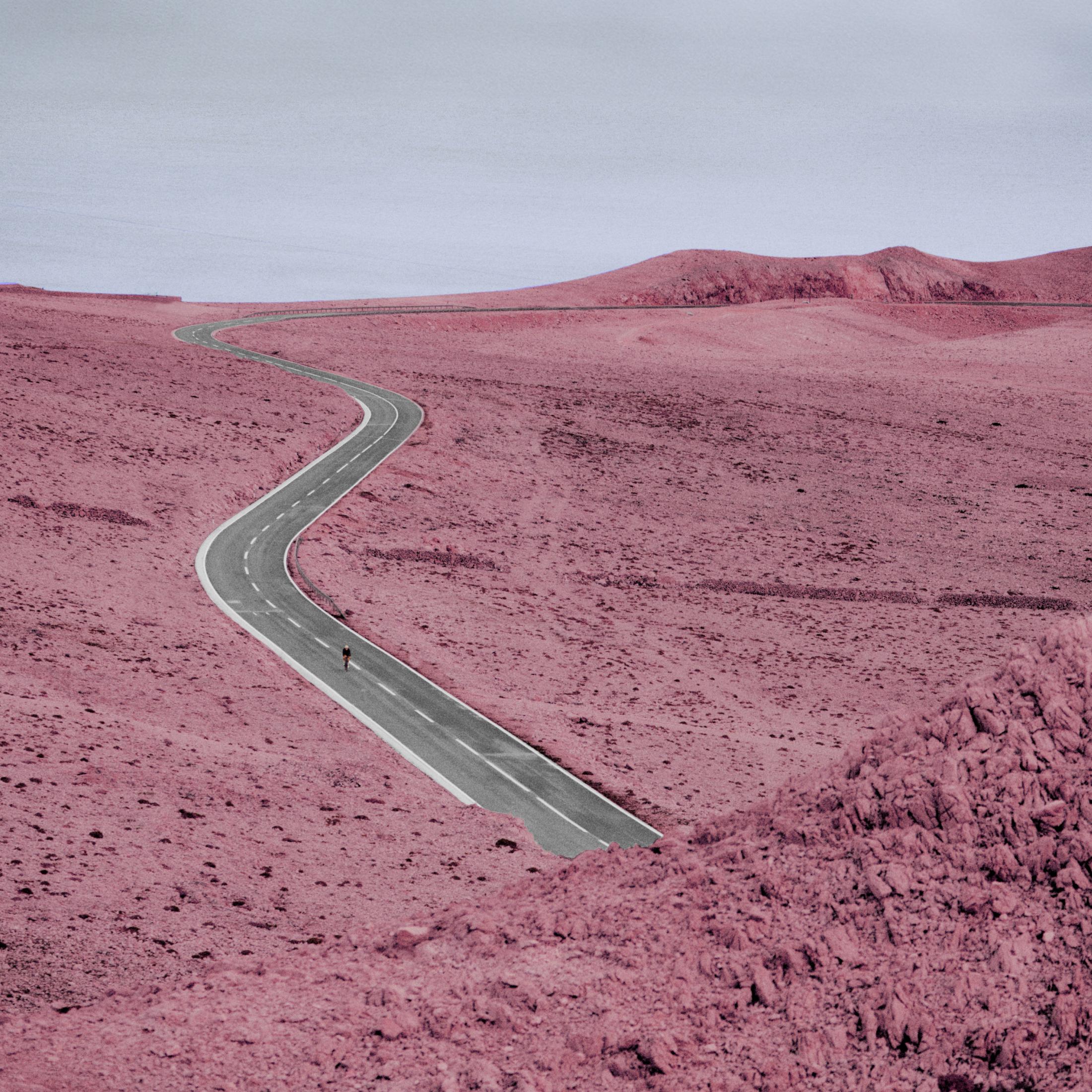Winding road through pink-tinted desert landscape with distant hills